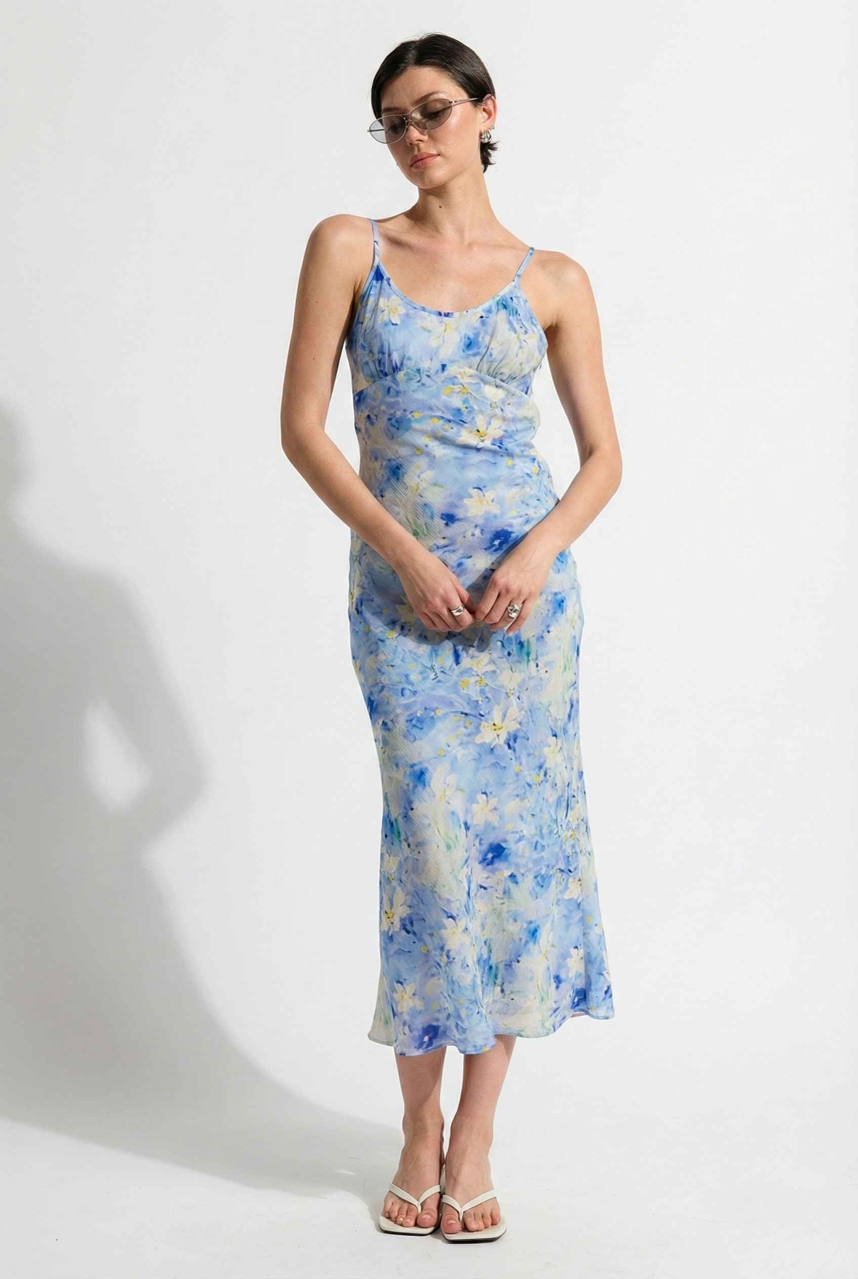 Woman wearing a Iris Midi Light Blue Floral Satin Slip Dress against a white background