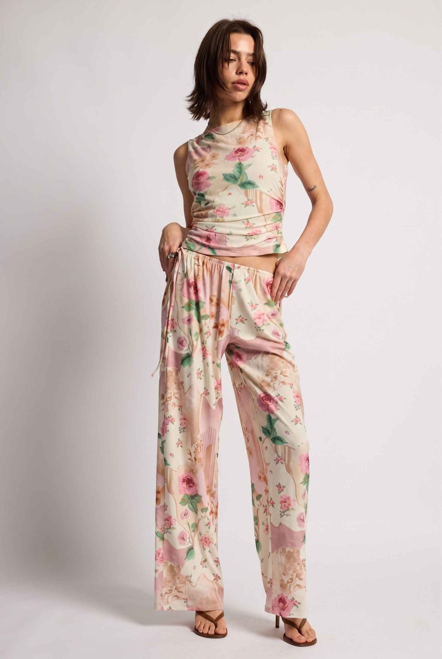 Model wearing Isabella Floral Wide-Leg Pants in Rose Floral High-Waist Trousers paired with matching high-neck tank top and heeled sandals