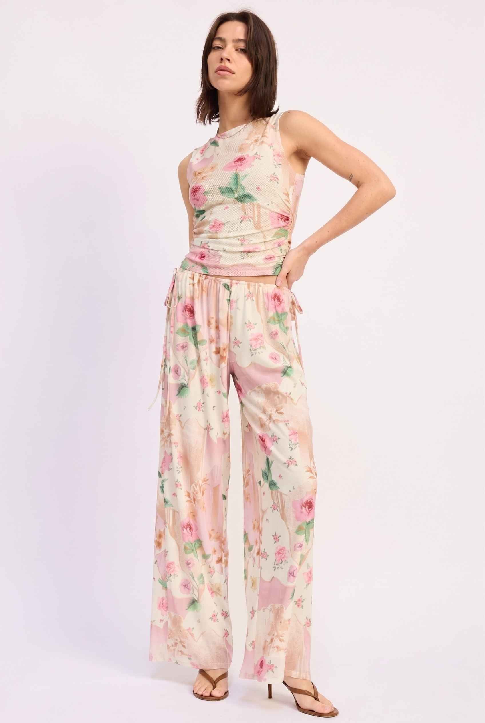 Model wearing Isabella Floral Wide-Leg Pants in Rose Floral High-Waist Trousers paired with matching high-neck tank top and heeled sandals