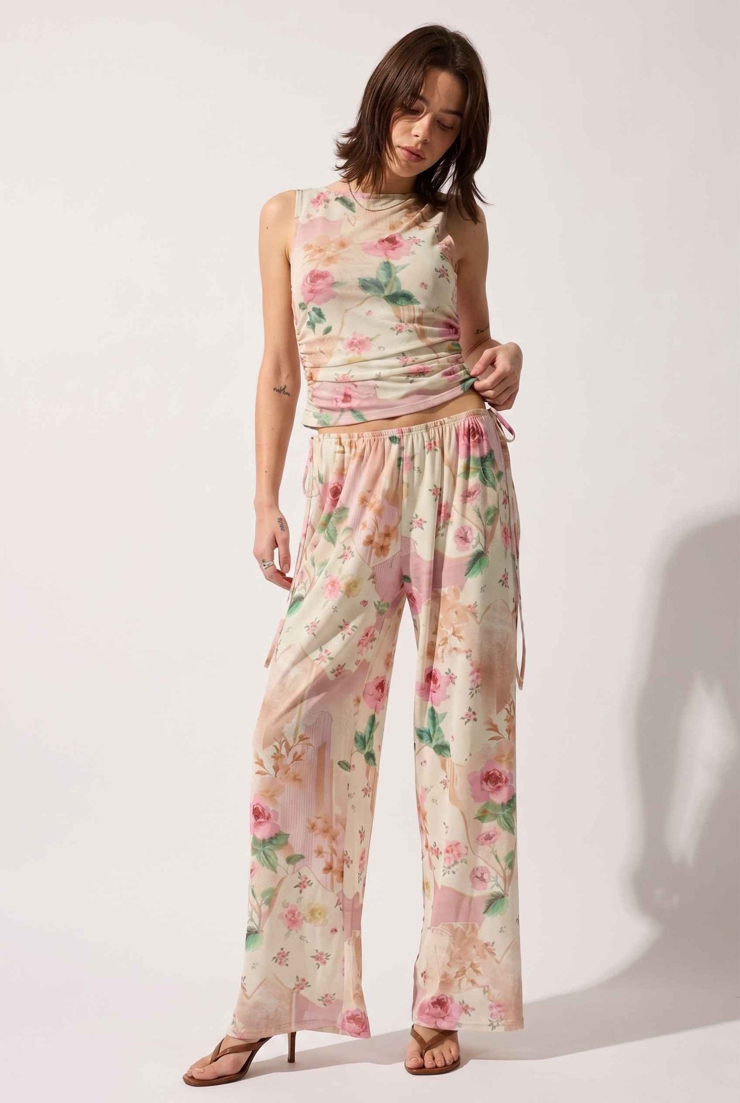 Model wearing Isabella Floral Wide-Leg Pants in Rose Floral High-Waist Trousers paired with matching high-neck tank top and heeled sandals