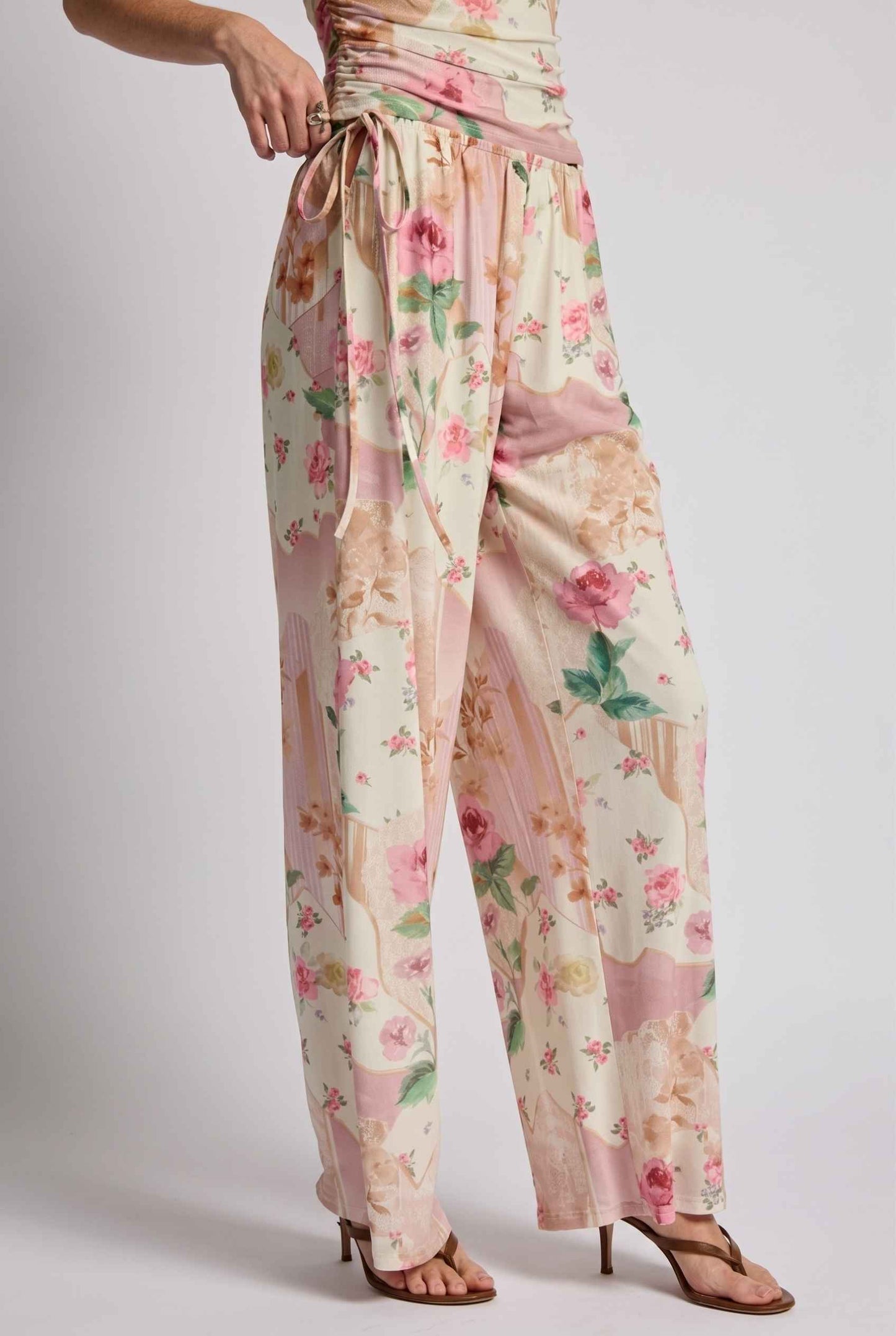 Model wearing Isabella Floral Wide-Leg Pants in Rose Floral High-Waist Trousers paired with matching high-neck tank top and heeled sandals