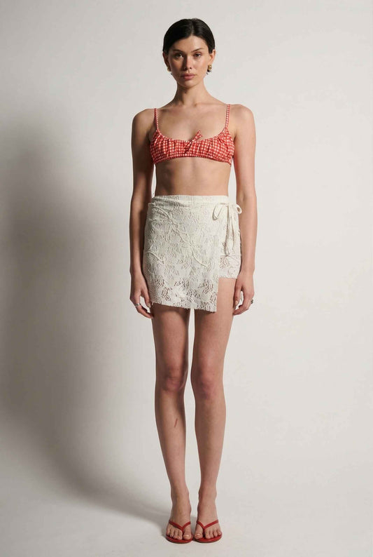 Model wearing Isla Skirt in Ivory Floral Lace Mini Wrap Skirt & Swim Cover-Up with gingham bikini top and matching sandals