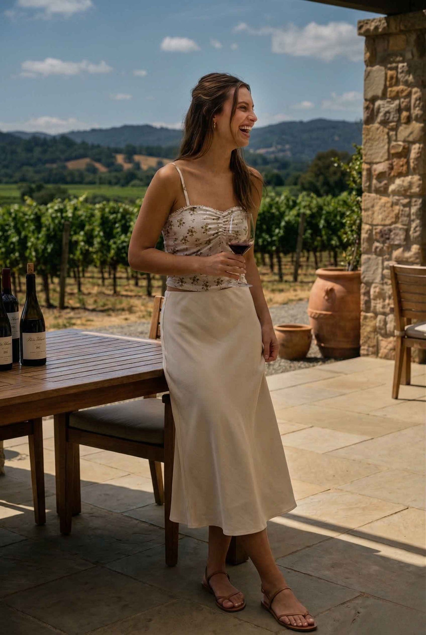 Woman wearing a Ivy Top Ivory Floral Crushed Velvet Lace Trim Cami standing outdoors in a vineyard holding a glass of wine