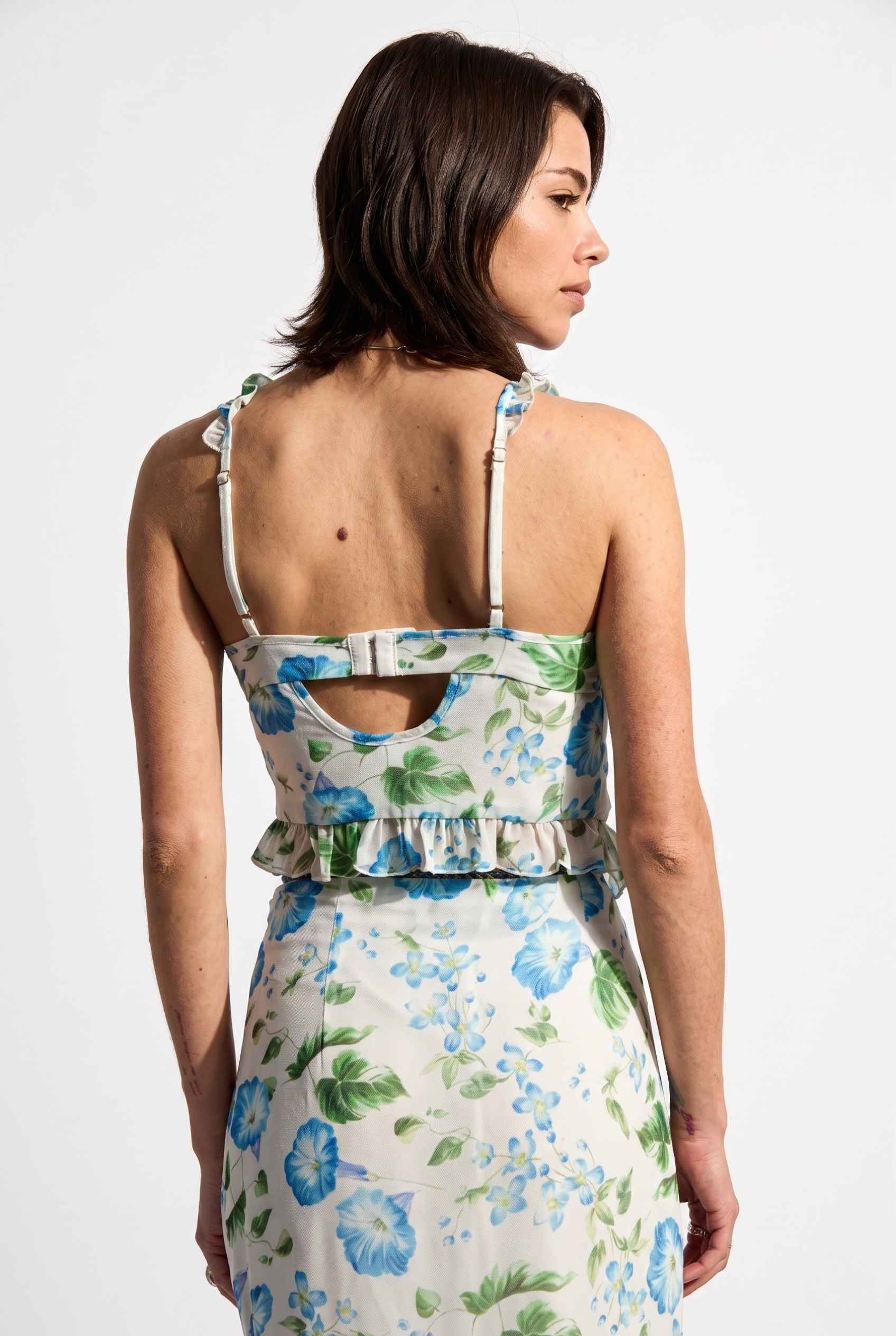 Model wearing Julia Asymmetrical Floral Bustier Top Ruffle Trim Top in Blue paired with matching maxi skirt back view bra closure design
