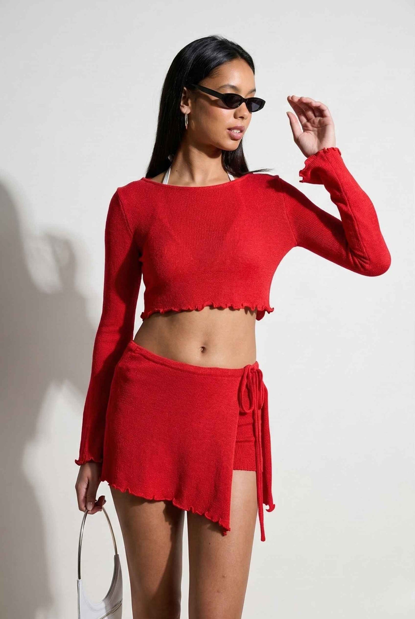 Woman wearing a Kaia Top Red Sheer Knit Boat Neck Long Sleeve Crop with a white background