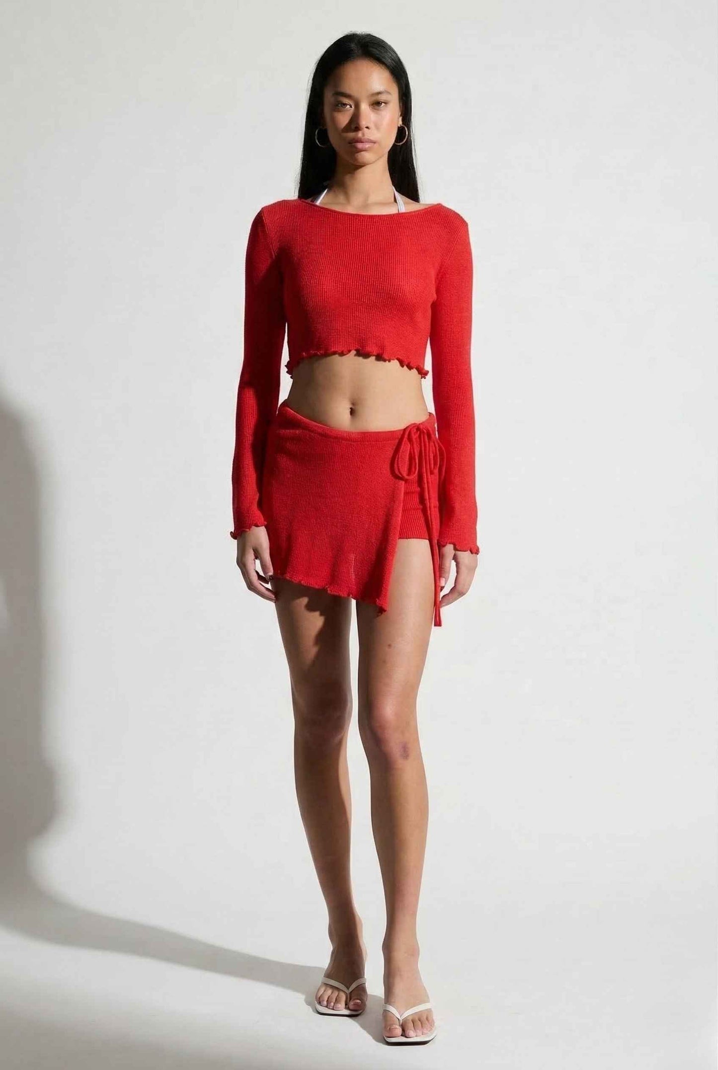 Woman wearing a Kaia Top Red Sheer Knit Boat Neck Long Sleeve Crop on a white background