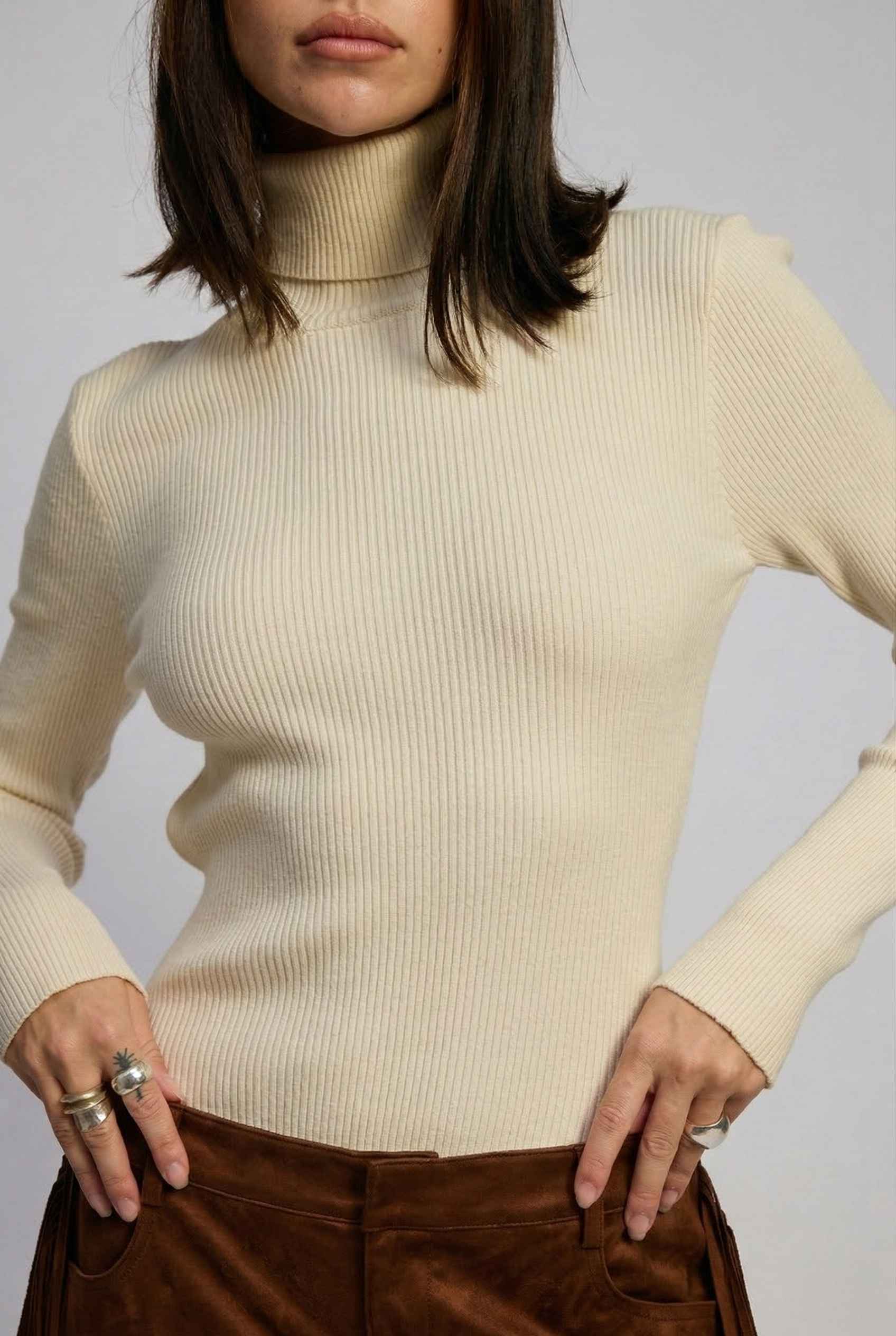 Model wearing Kiera Bodysuit Ribbed Knit Turtleneck Long Sleeve Bodysuit in Ivory with suede shorts