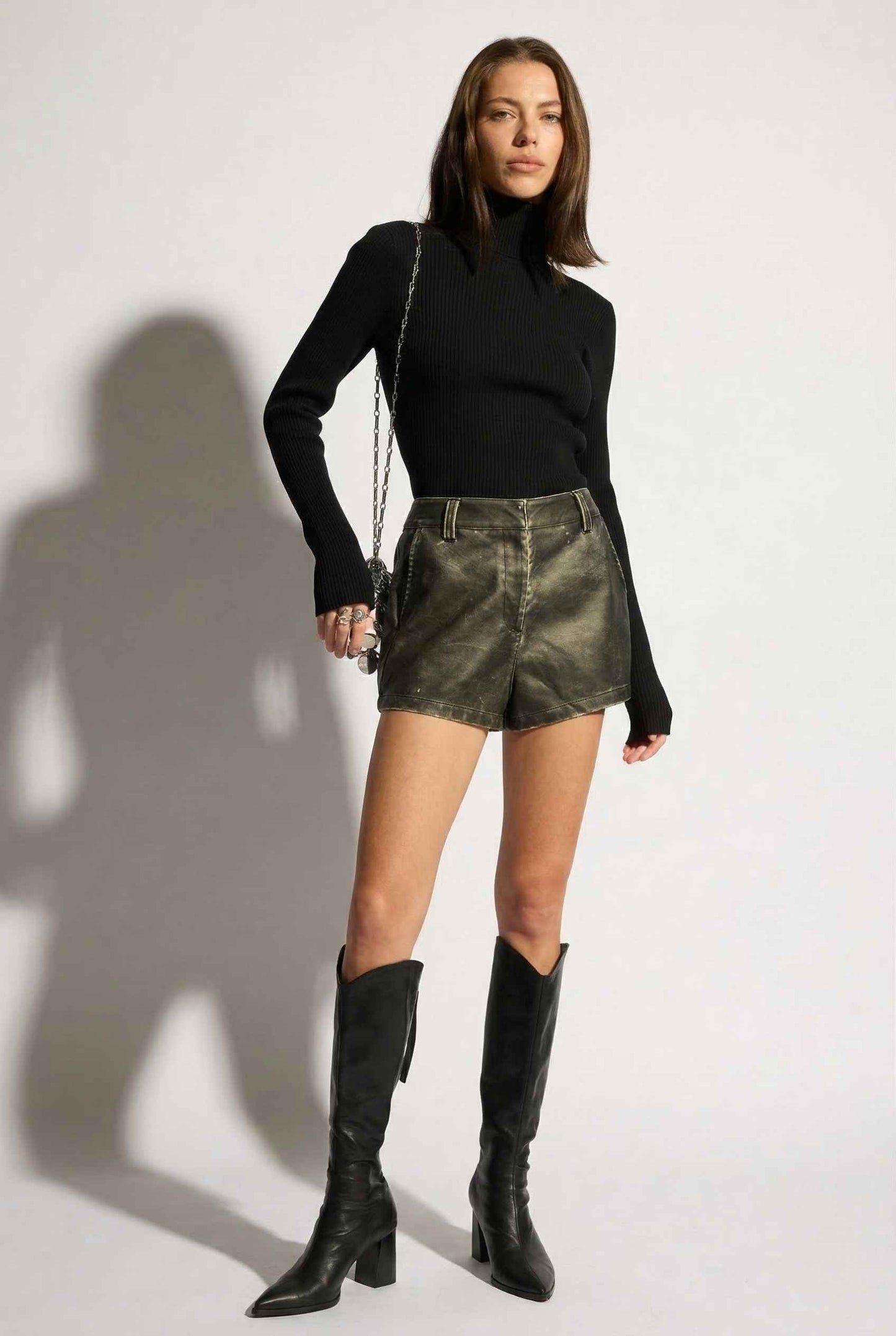 Model wearing Kiera Bodysuit Ribbed Knit Turtleneck Long Sleeve Bodysuit in Black with leather shorts and tall boots