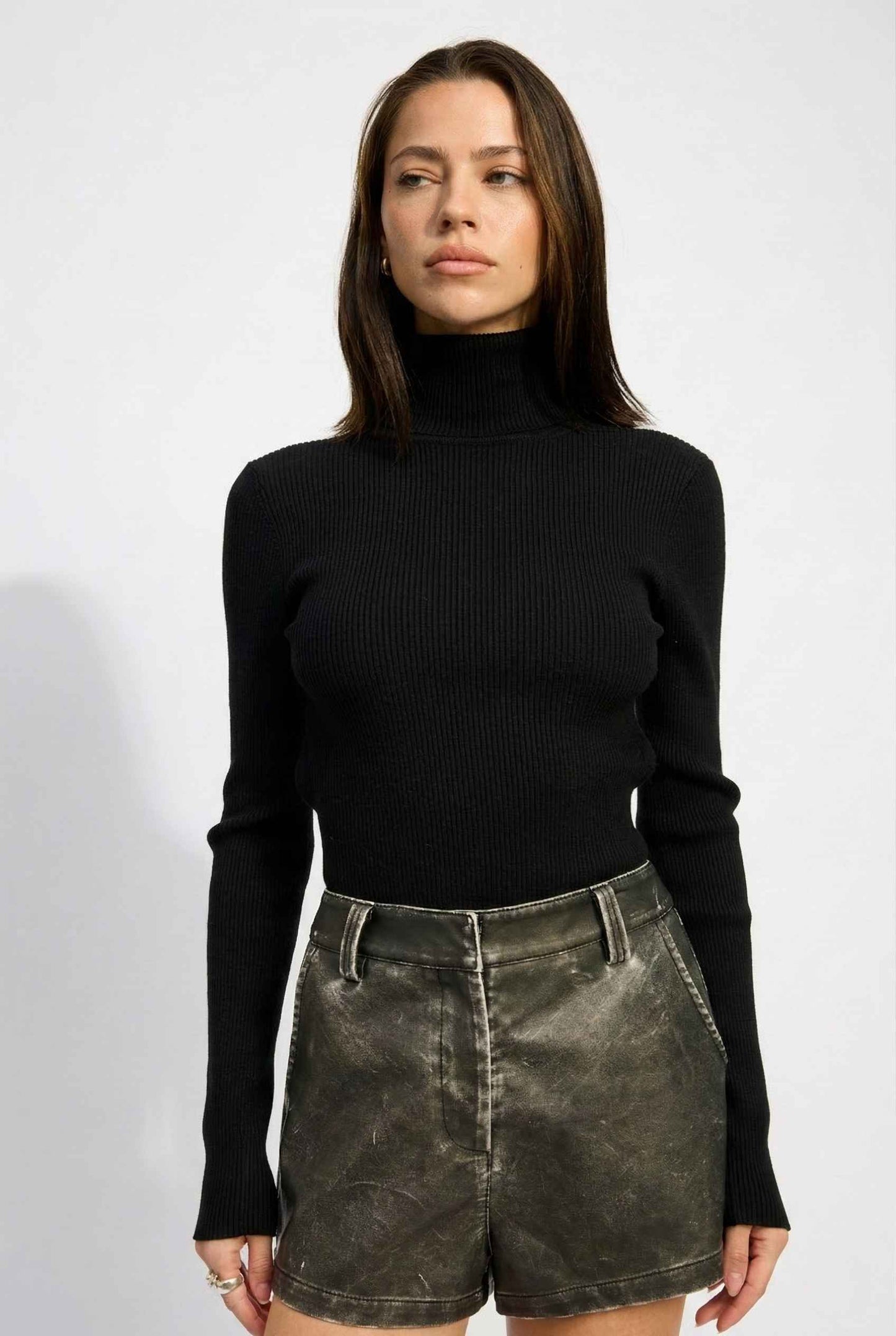 Model wearing Kiera Bodysuit Ribbed Knit Turtleneck Long Sleeve Bodysuit in Black with leather shorts