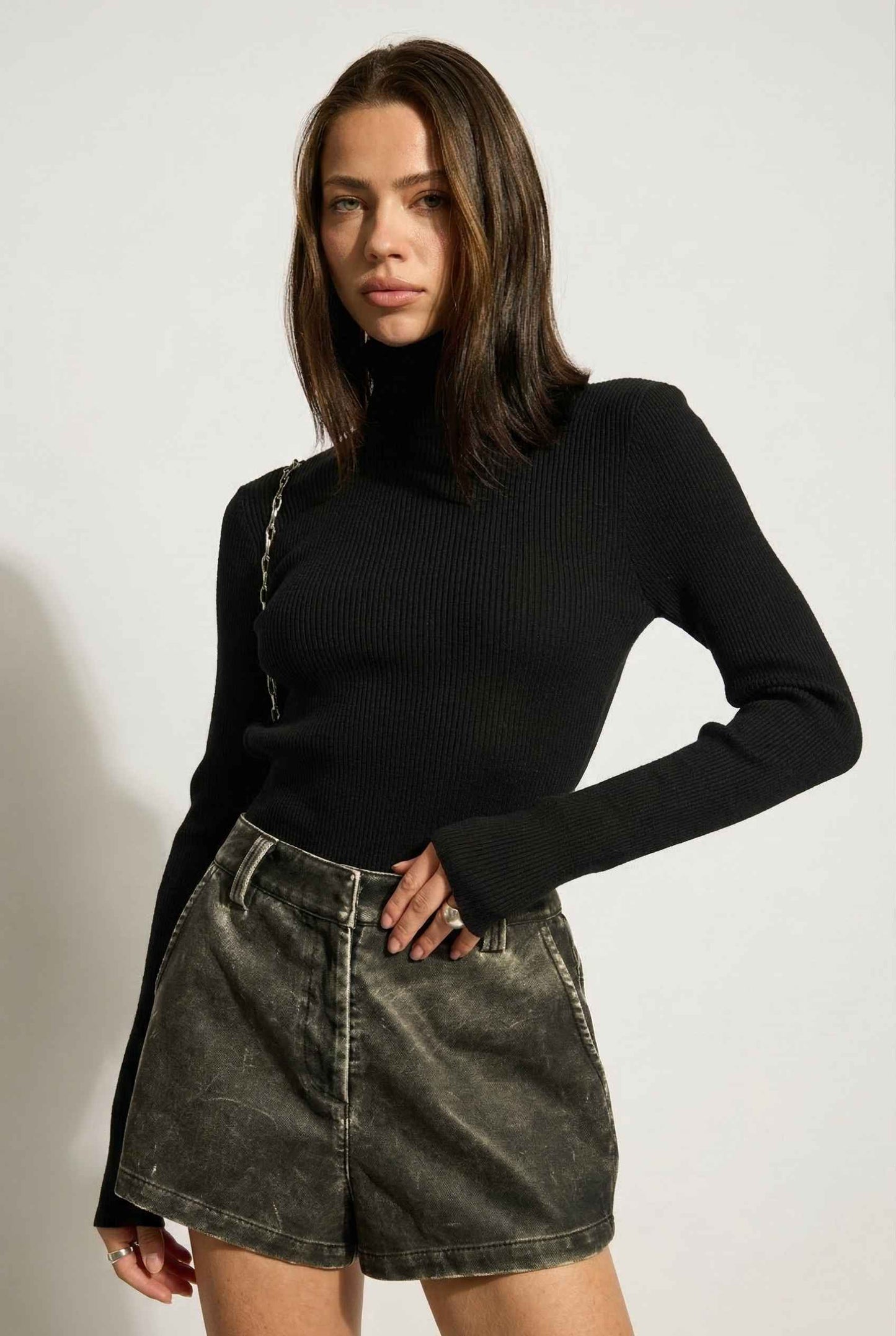 Model wearing Kiera Bodysuit Ribbed Knit Turtleneck Long Sleeve Bodysuit in Black with leather shorts