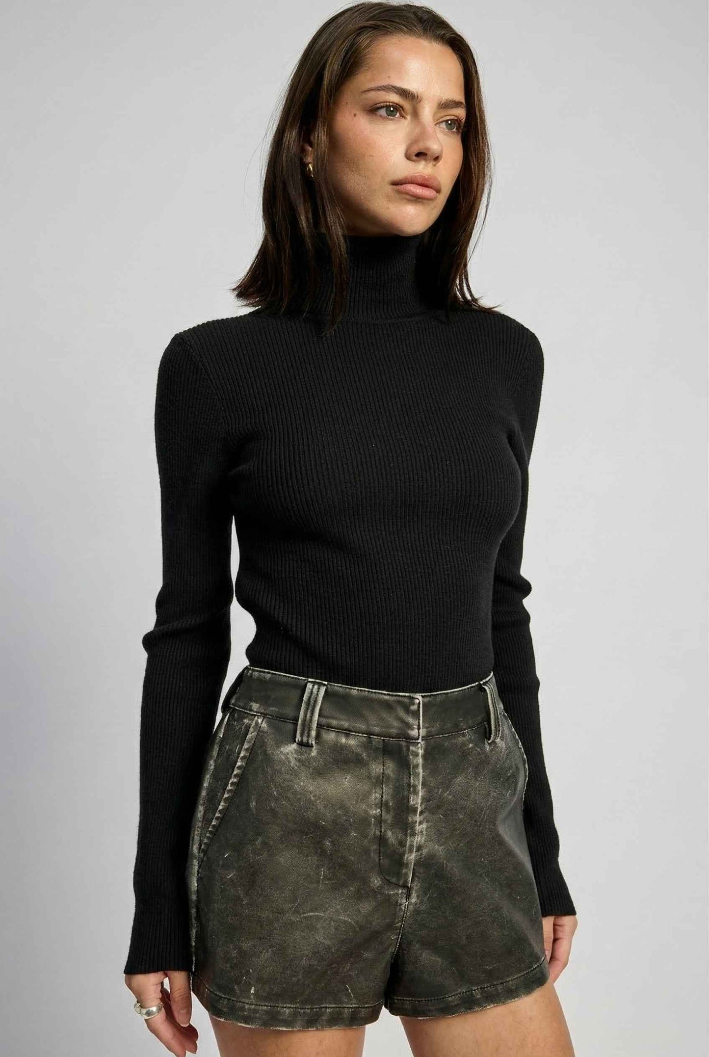 Model wearing Kiera Bodysuit Ribbed Knit Turtleneck Long Sleeve Bodysuit in Black with leather shorts 