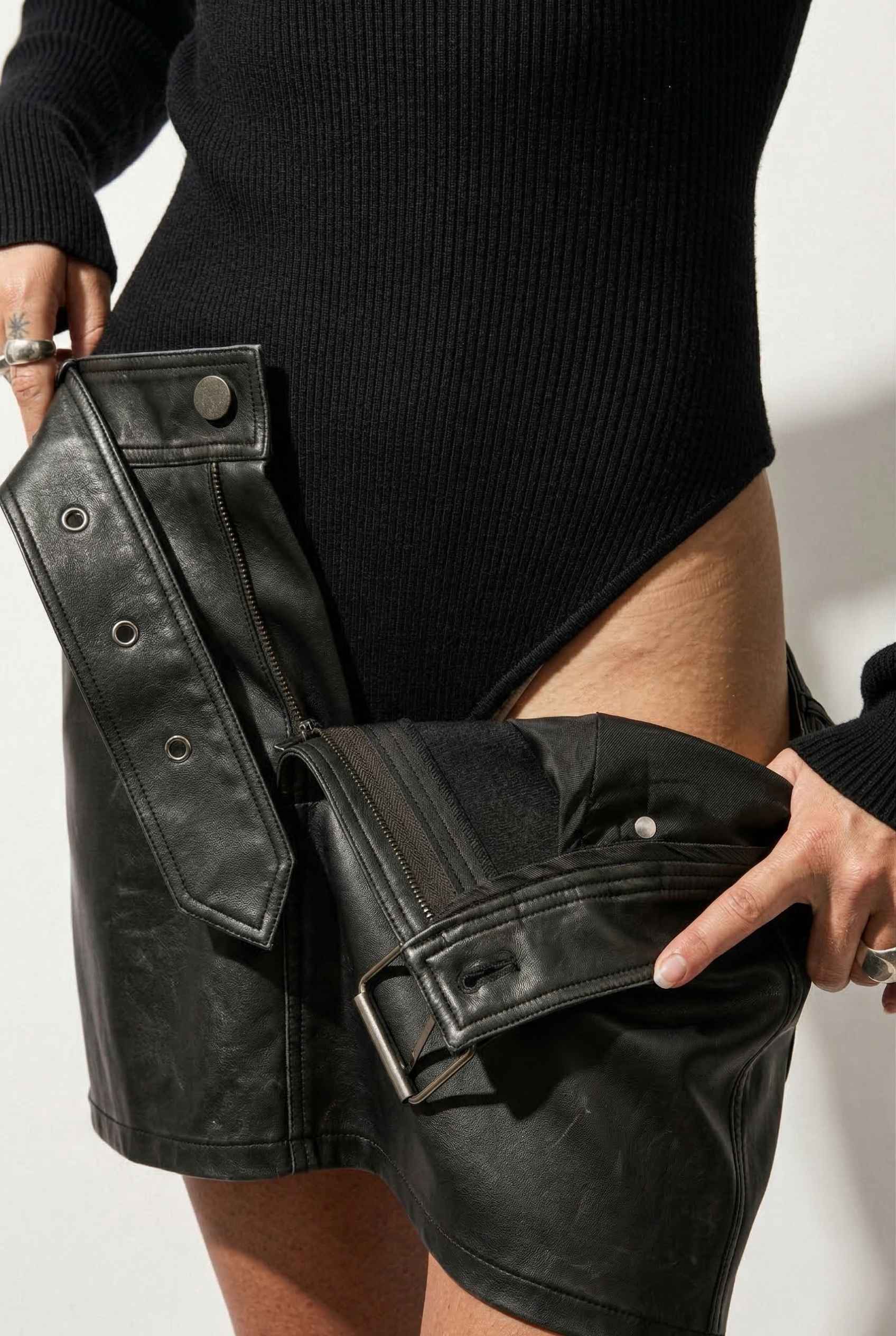 Model wearing Kiera Bodysuit Ribbed Knit Turtleneck Long Sleeve Bodysuit in Black with leather shorts