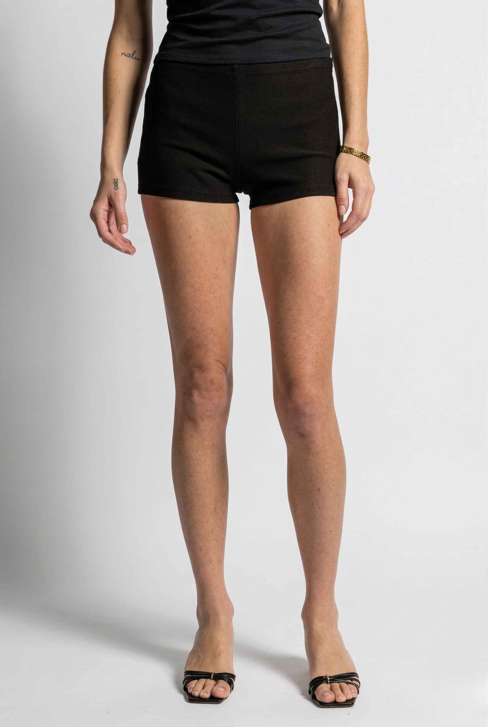 Woman wearing Kyra Shorts Black Rayon-Blend Knit Micro Biker Shorts on a plain background
