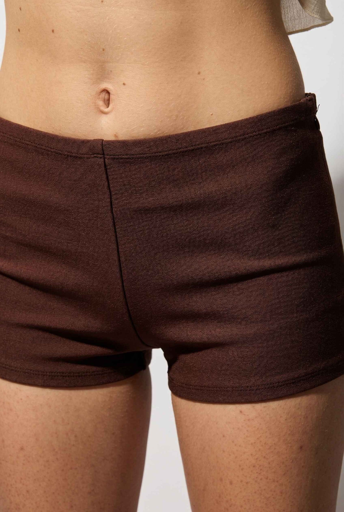 Kyra Shorts Brown Rayon-Blend Knit Micro Biker Shorts worn by a woman on a plain background