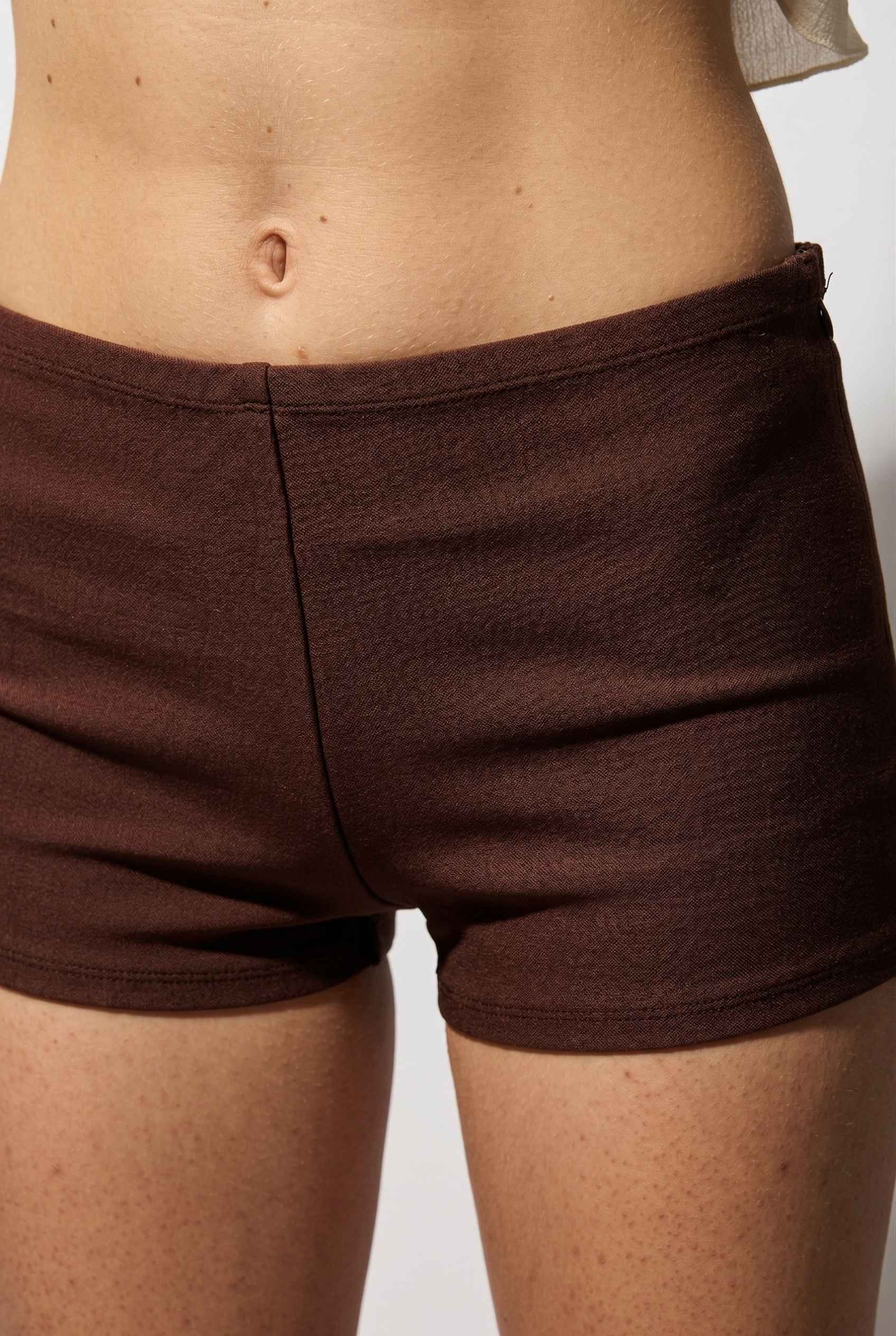 Kyra Shorts Brown Rayon-Blend Knit Micro Biker Shorts worn by a woman on a plain background