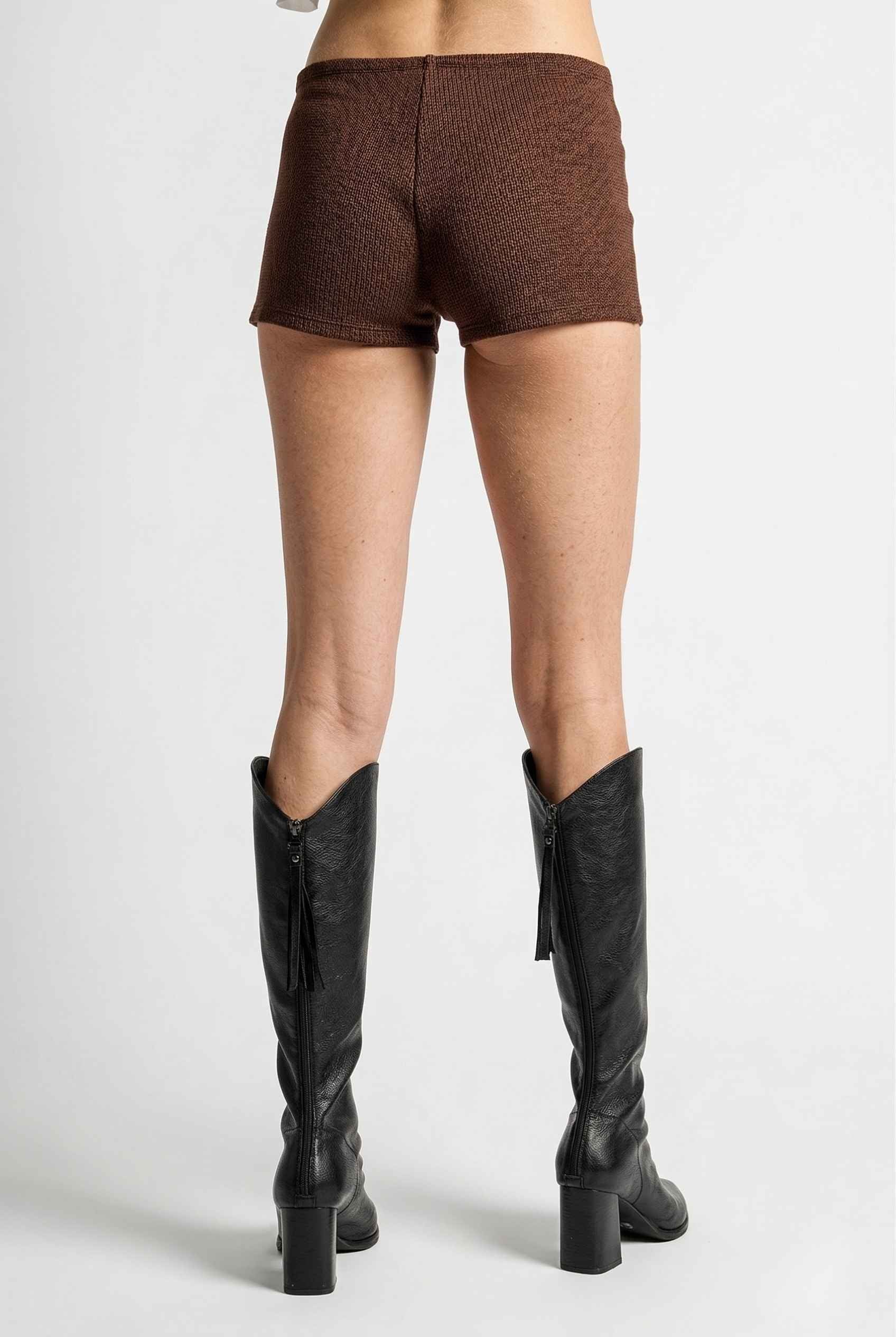Woman wearing Kyra Shorts Brown Rayon-Blend Knit Micro Biker Shorts and knee-high boots on a white background
