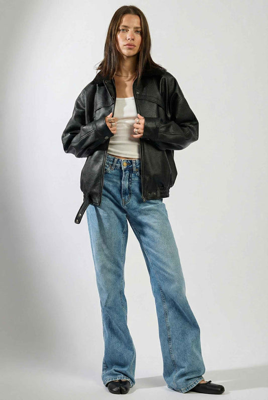 Model wearing Lennox Jacket | Black Vegan Leather Bomber with Shearling Trim with top, jeans, and ballet flats against plain background