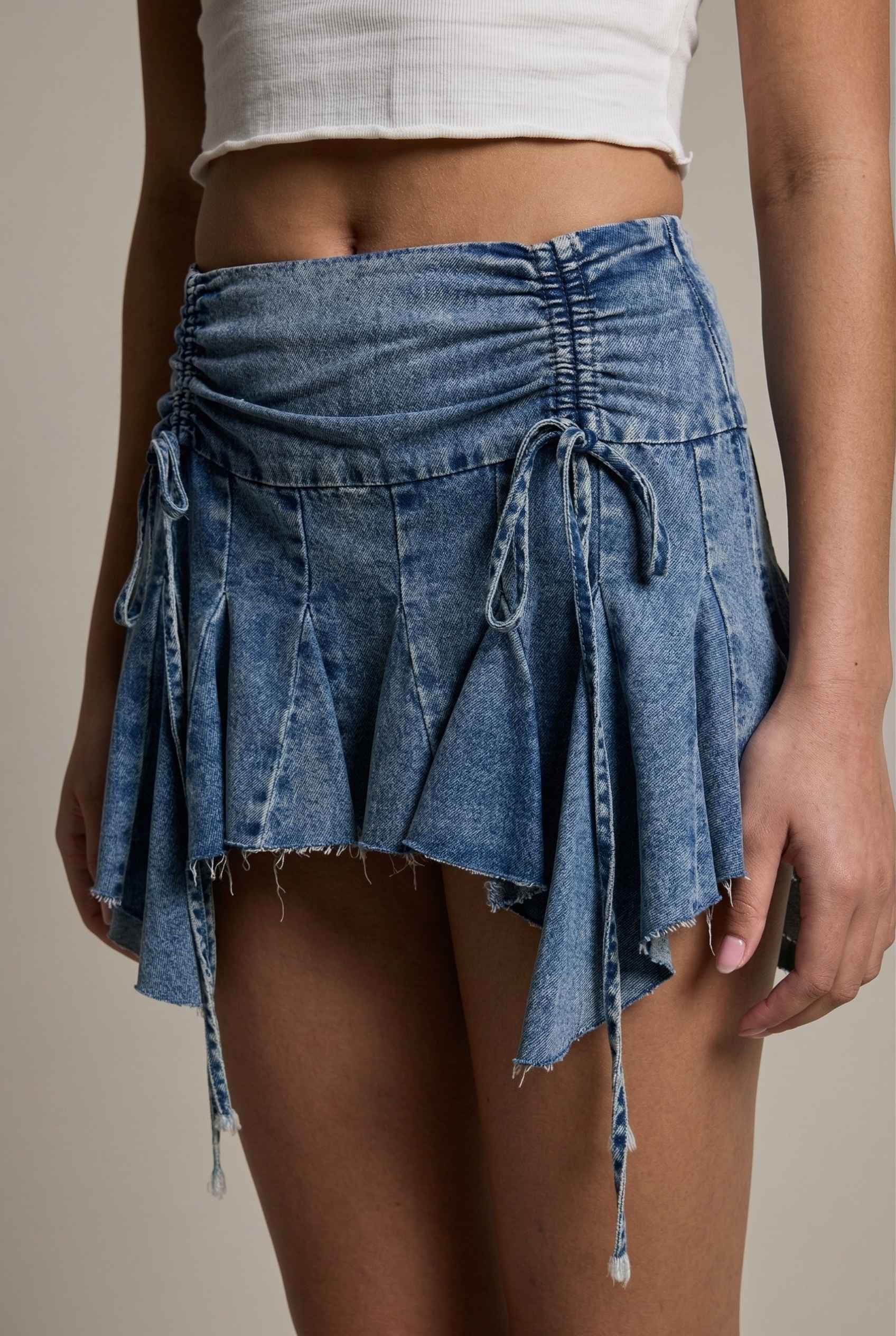 Model wearing Lola Skirt in light Blue Denim Ruched Waist Mini with Ruffle Hem with basic cropped t-shirt