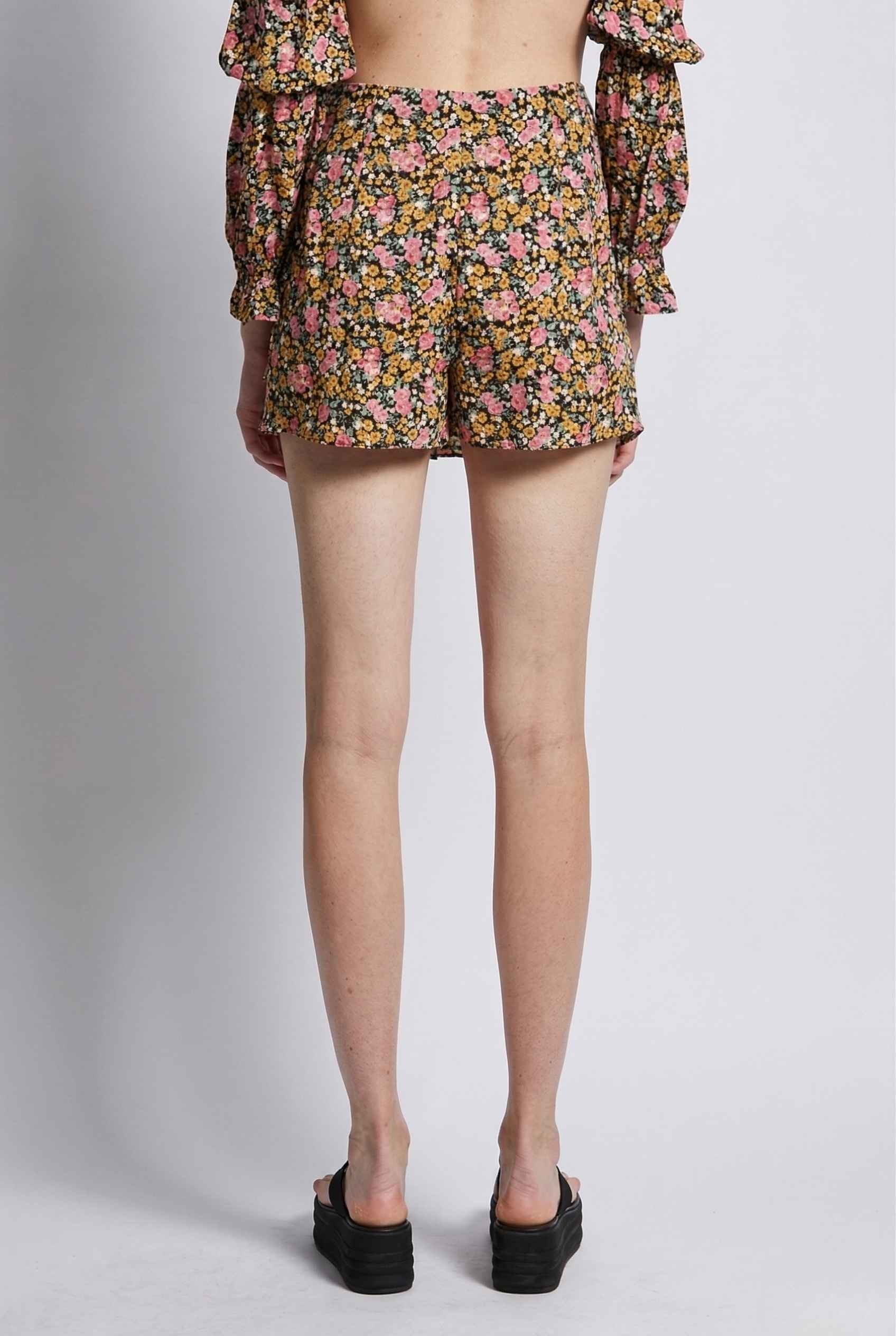 Woman wearing Lyla Skort Black Ditsy Floral Linen-Blend Ruffle Mini Skort on a plain background