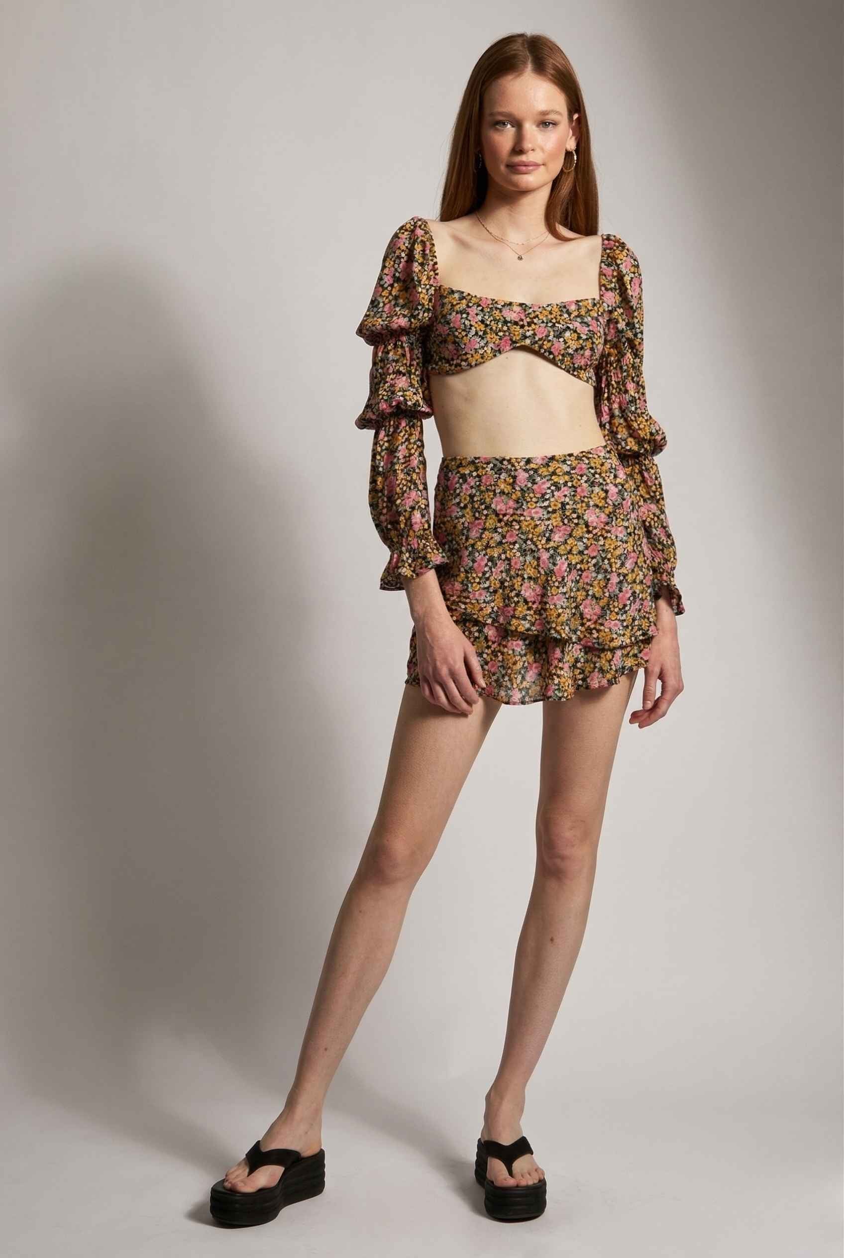 Woman wearing a Lyla Skort Black Ditsy Floral Linen-Blend Ruffle Mini Skort on a plain background