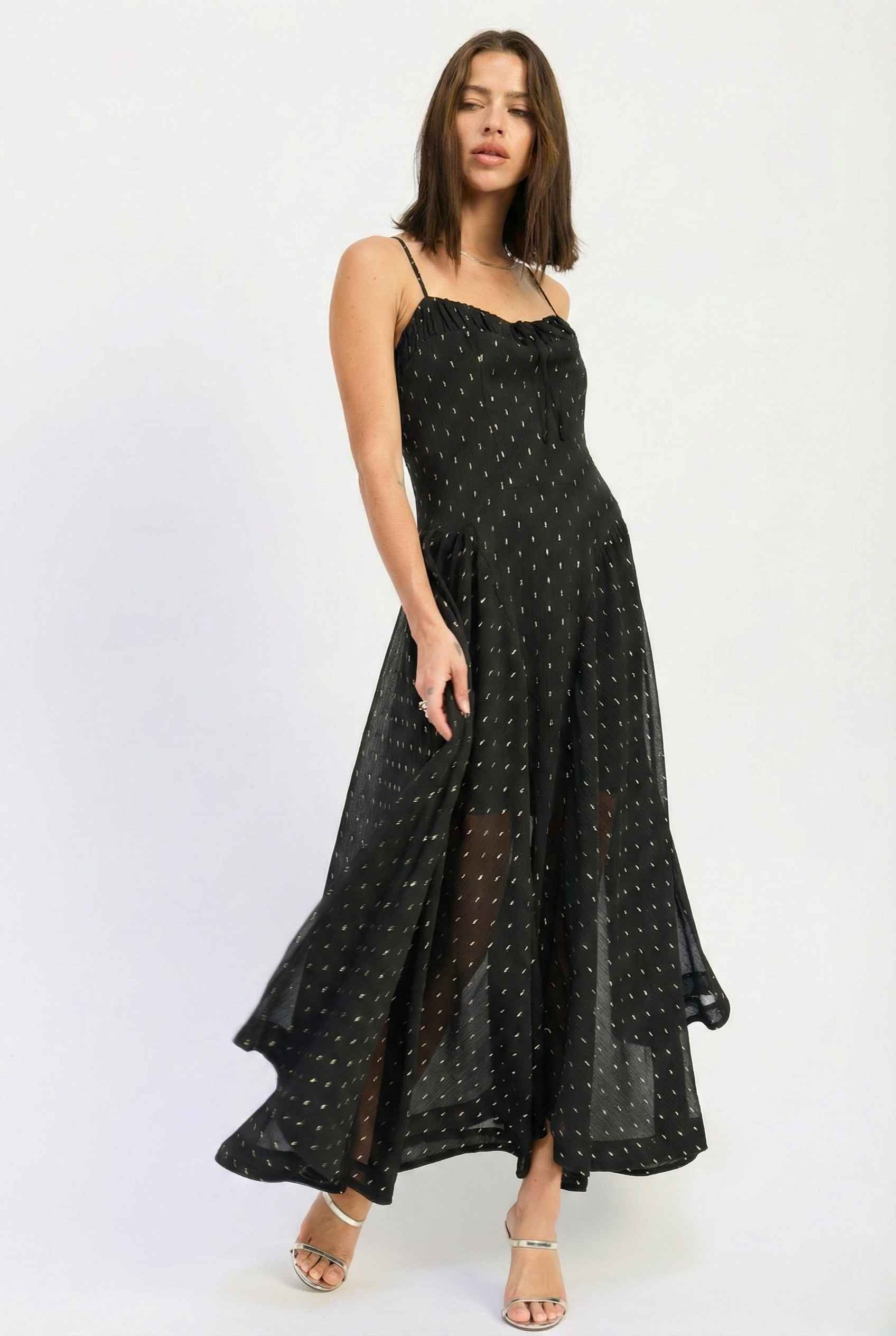 Woman wearing a Lyra Maxi Black Metallic Fleck Chiffon Dress with white polka dots on a white background