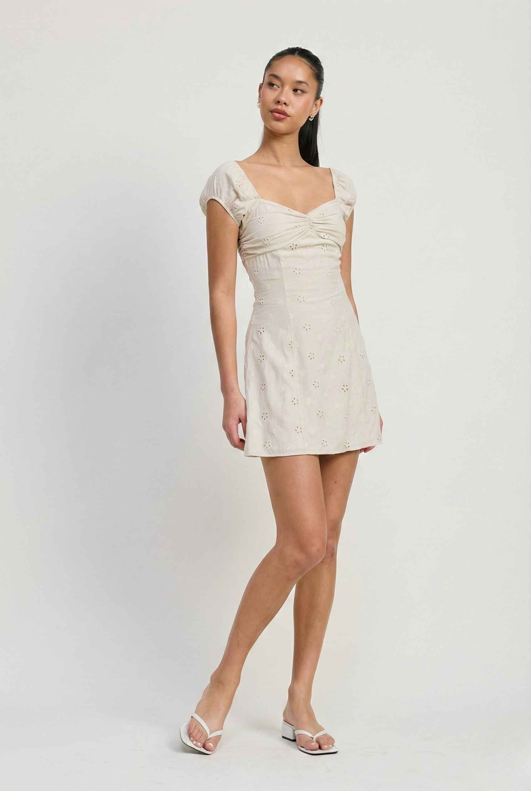 Woman wearing a Maeve Mini Ivory Eyelet Ruched Puff Sleeve Dress on a plain background
