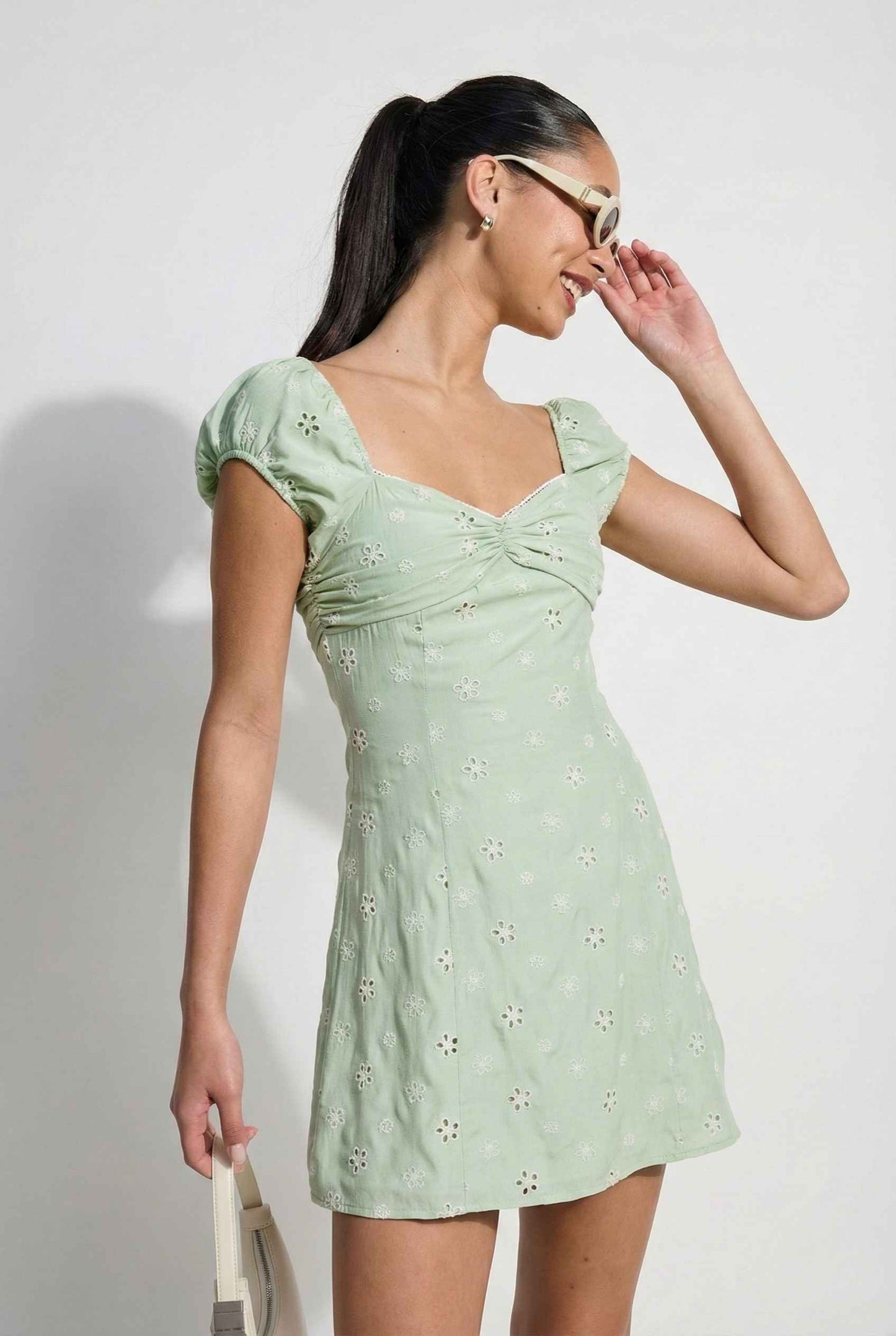 Woman wearing a Maeve Mini Mint Eyelet Ruched Puff Sleeve Dress with floral details against a white background