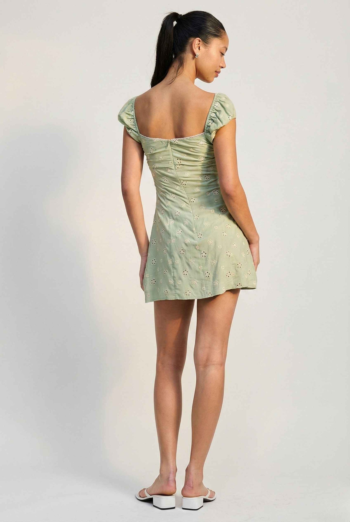 Woman wearing a lMaeve Mini Mint Eyelet Ruched Puff Sleeve Dress with a plain background