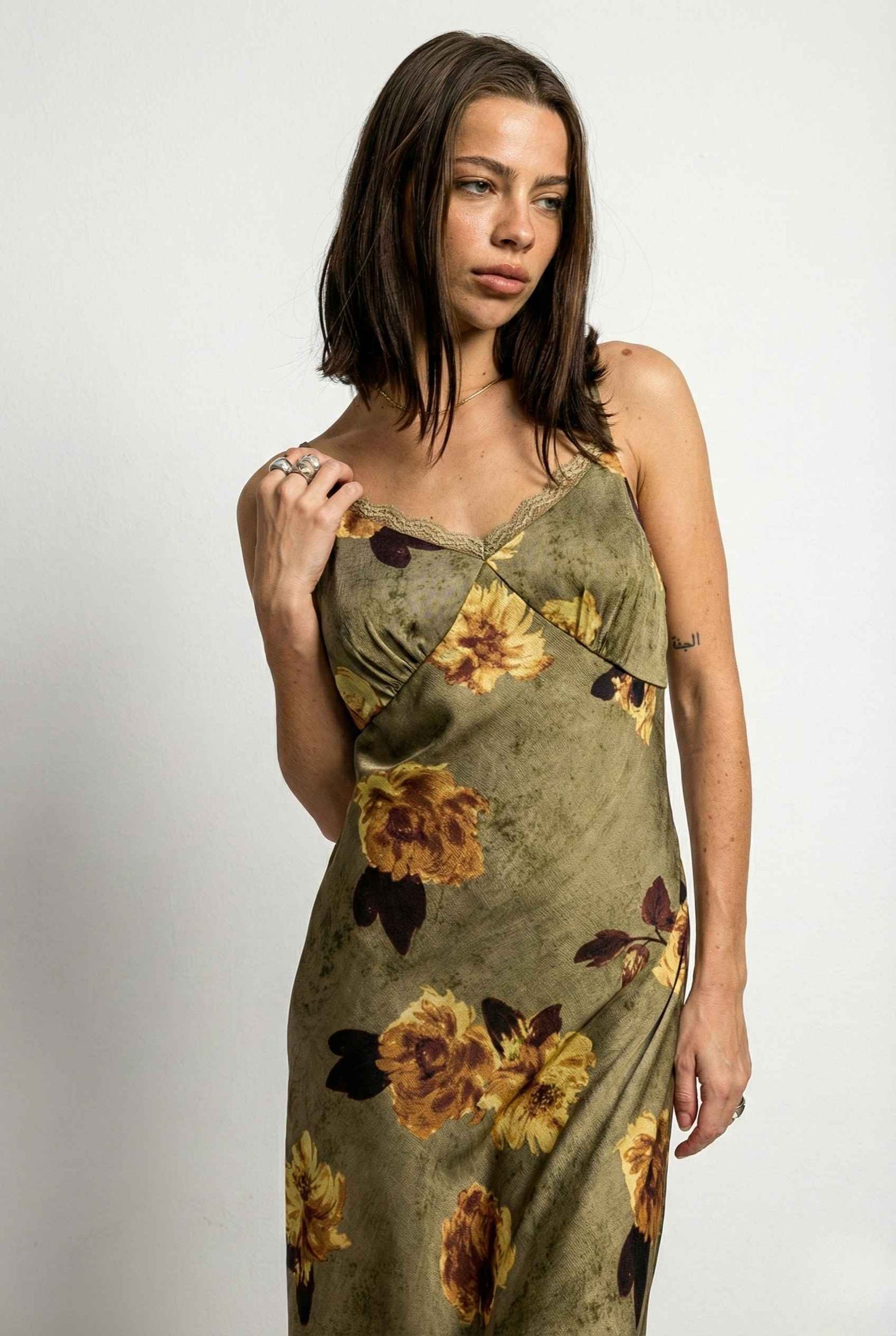 Woman wearing a Marcella Maxi Olive Floral Satin Slip Dress against a plain background