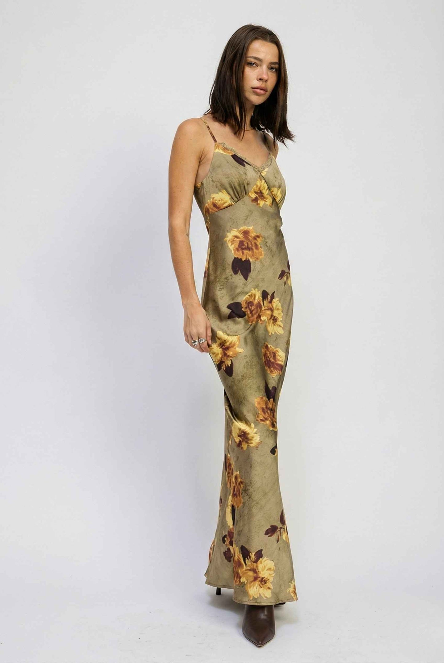 Woman wearing a Marcella Maxi Olive Floral Satin Slip Dress on a white background