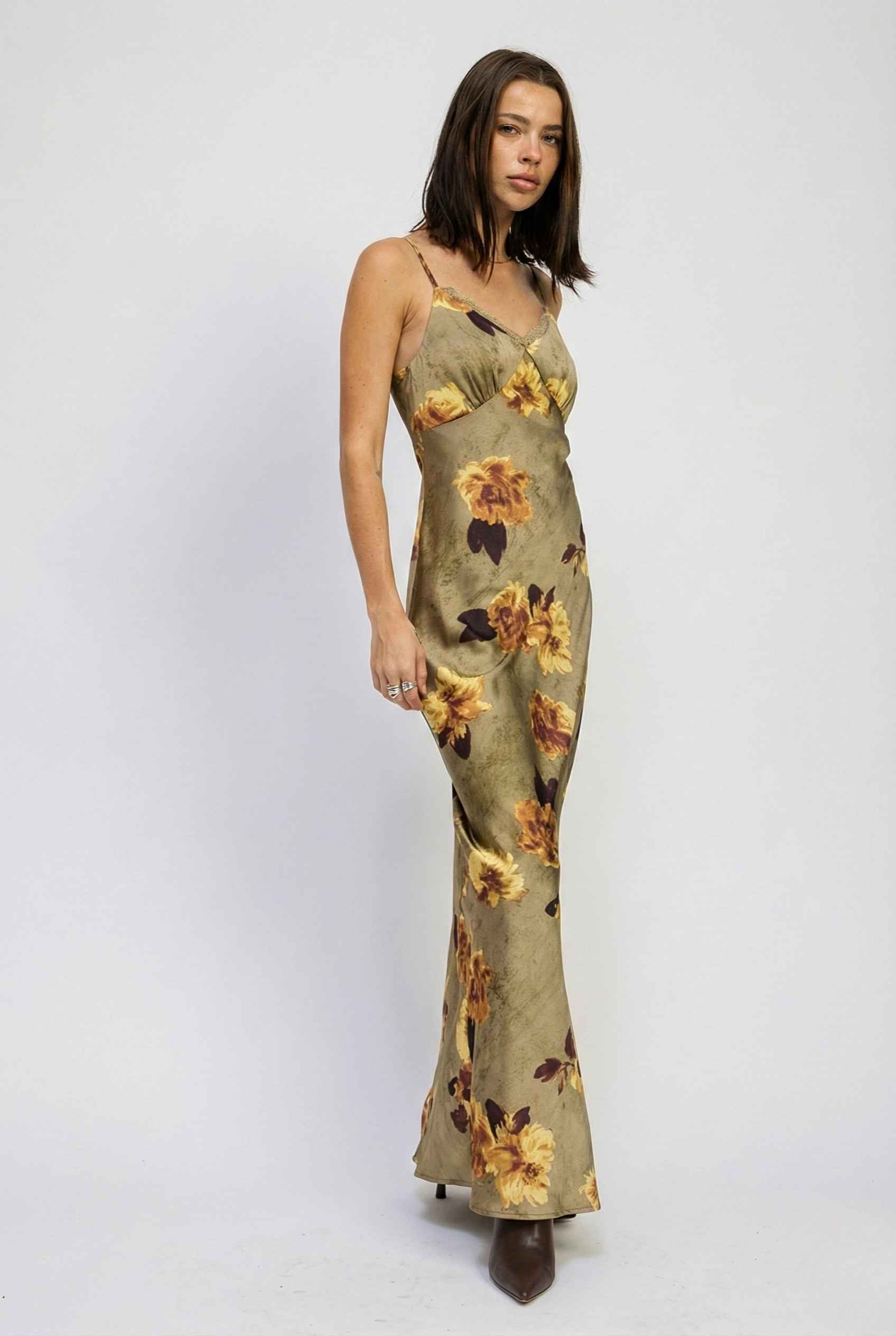 Woman wearing a Marcella Maxi Olive Floral Satin Slip Dress on a white background