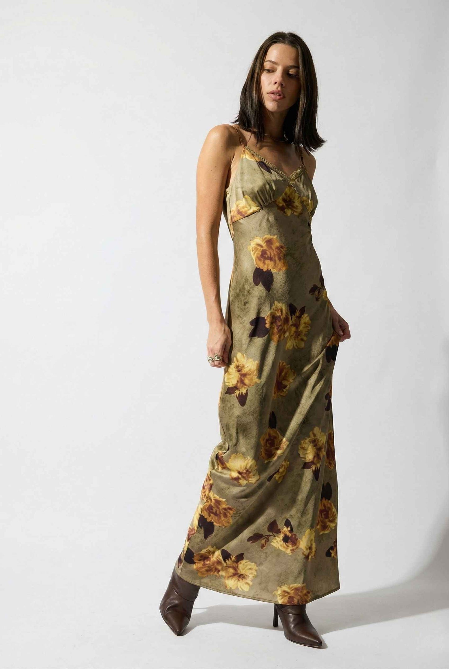 Woman wearing a Marcella Maxi Olive Floral Satin Slip Dress on a white background