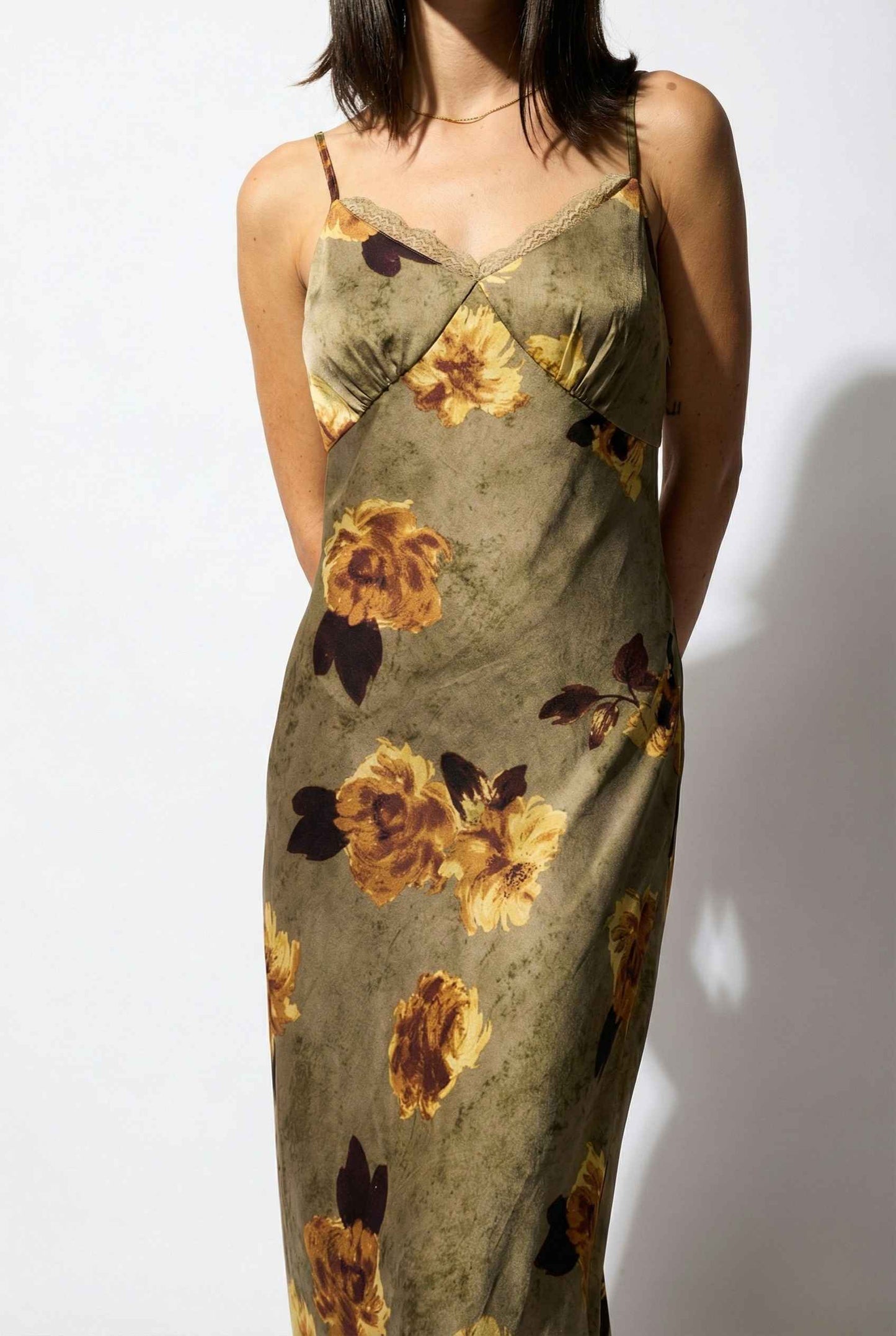 Woman wearing a Marcella Maxi Olive Floral Satin Slip Dress against a white background