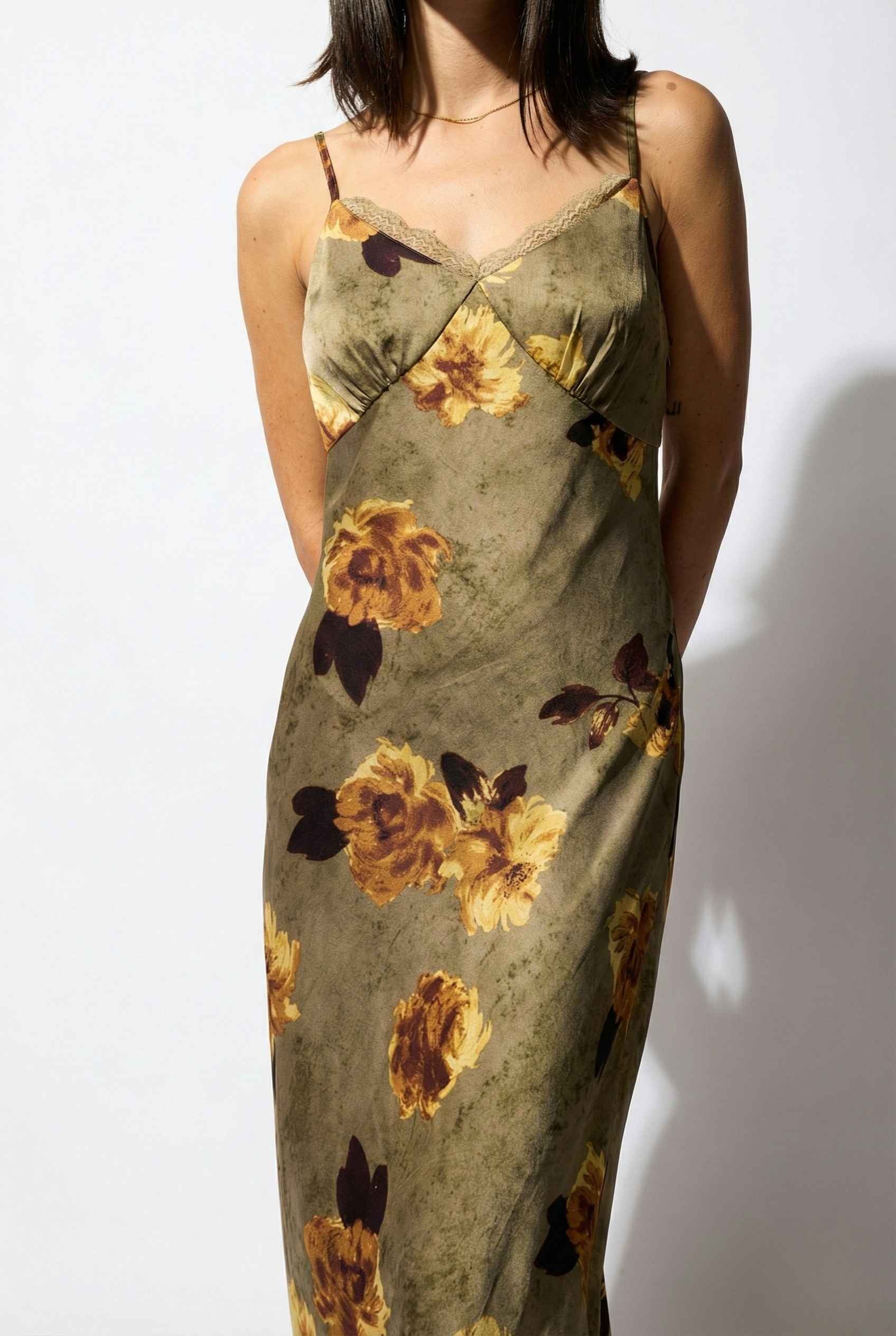 Woman wearing a Marcella Maxi Olive Floral Satin Slip Dress against a white background