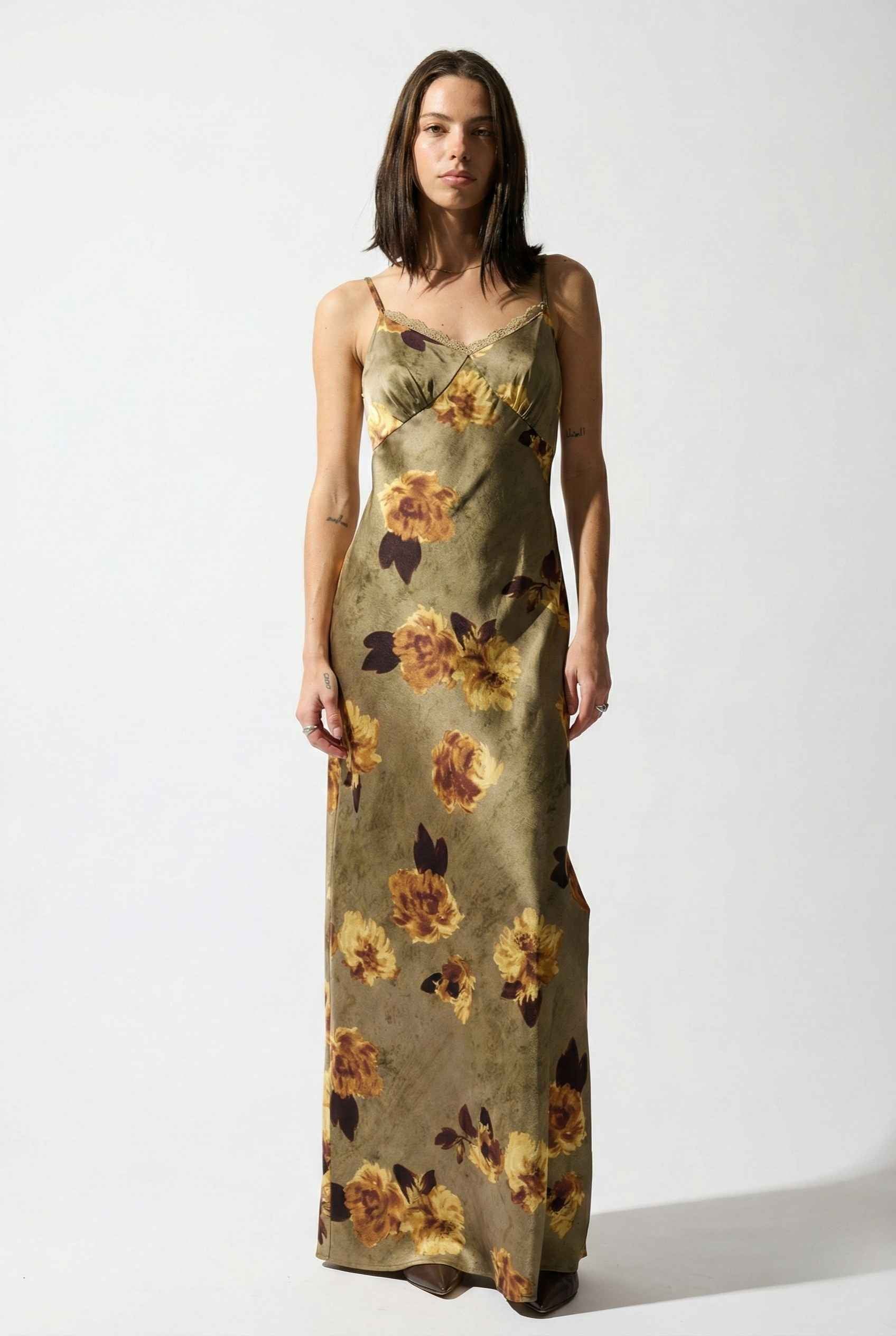 Woman wearing a Marcella Maxi Olive Floral Satin Slip Dress on a white background