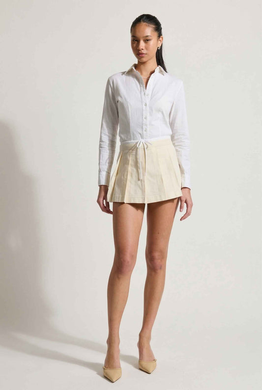 Model wearing Margo Skort in Ivory Poplin Cotton Twill Pleated Mini Skort paired with crisp poplin blouse and basic heels