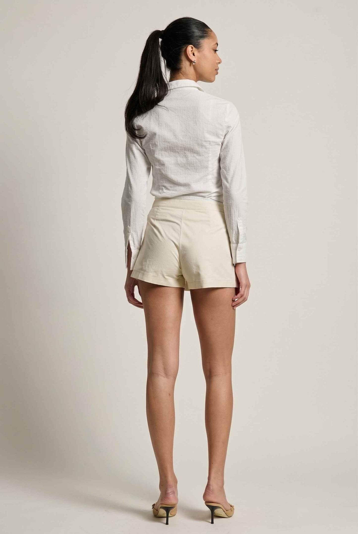 Model wearing Margo Skort in Ivory Poplin Cotton Twill Pleated Mini Skort paired with crisp poplin blouse and basic heels