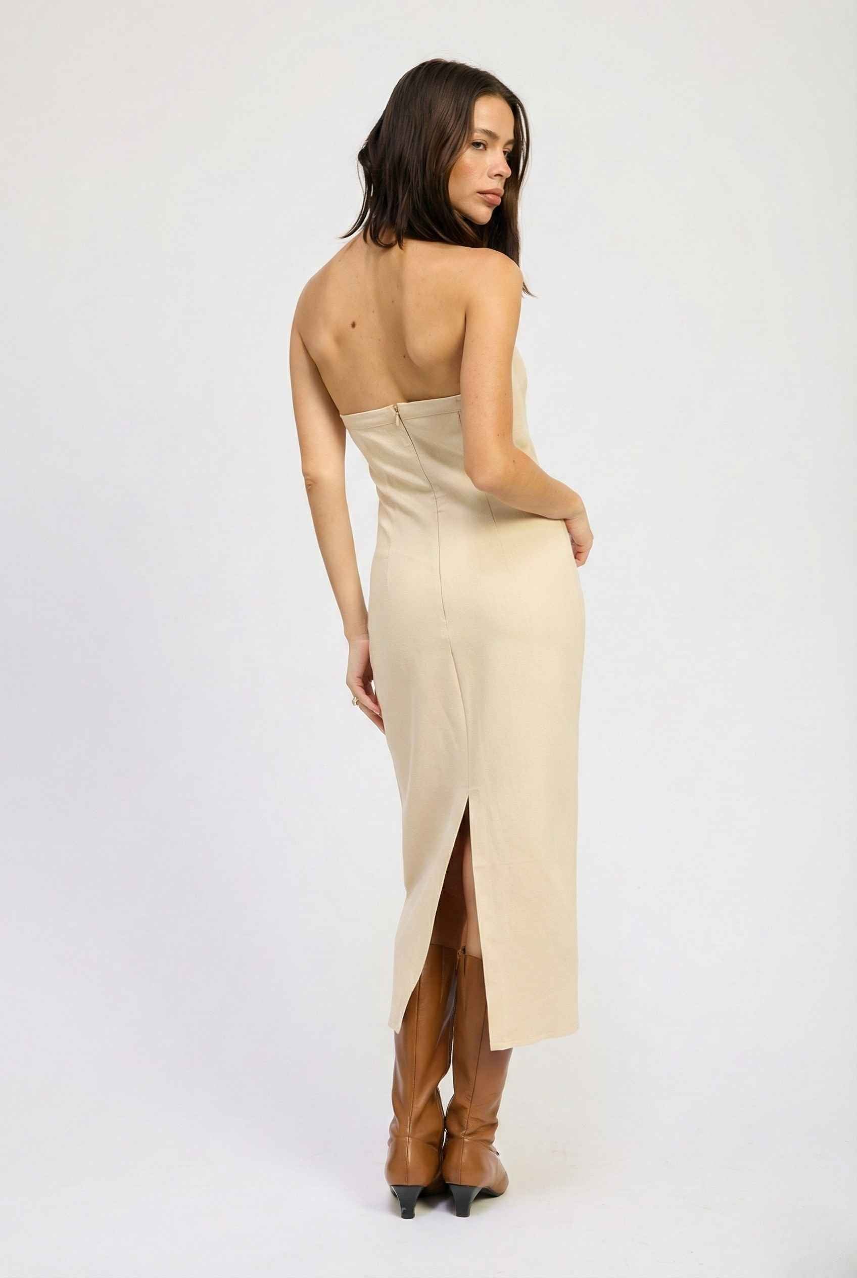 Woman wearing a Mercer Midi Taupe Halter Hardware Dress with a slit on a white background