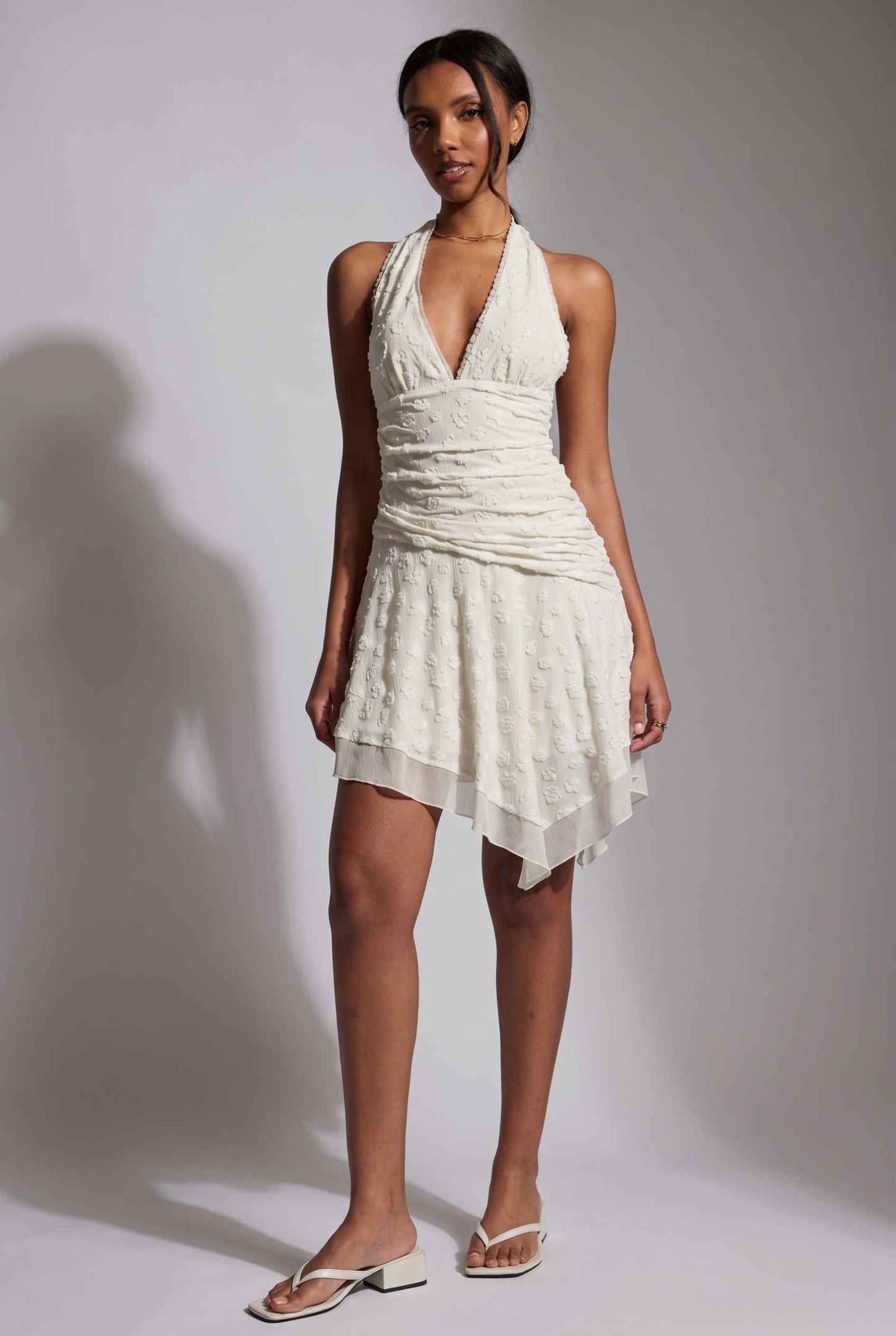 Model wearing Mikala Ruched Halter Mini Dress in Ivory Cocktail Dress paired with minimalist heels