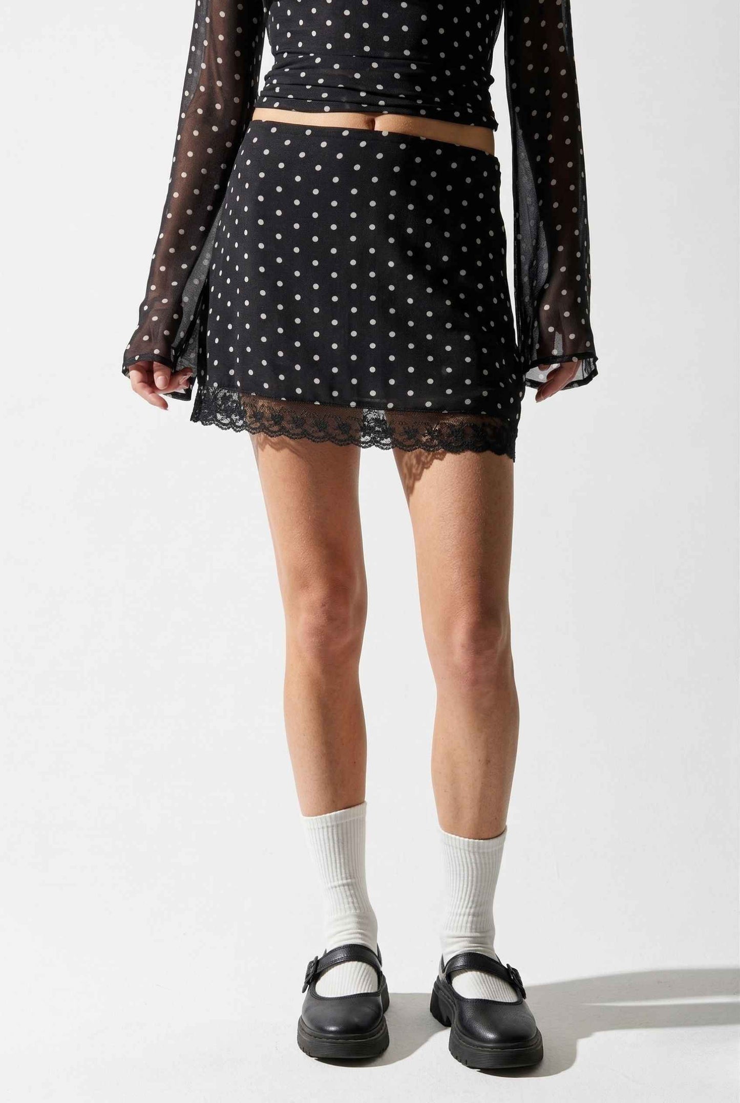 Woman wearing a Mila Skirt Black Polka Dot Mesh Mini Skirt with Lace Trim with sheer top on a white background