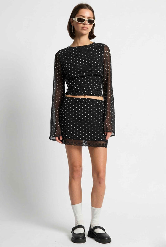 Woman wearing a Mila Skirt Black Polka Dot Mesh Mini Skirt with Lace Trim with sheer sleeves on a white background