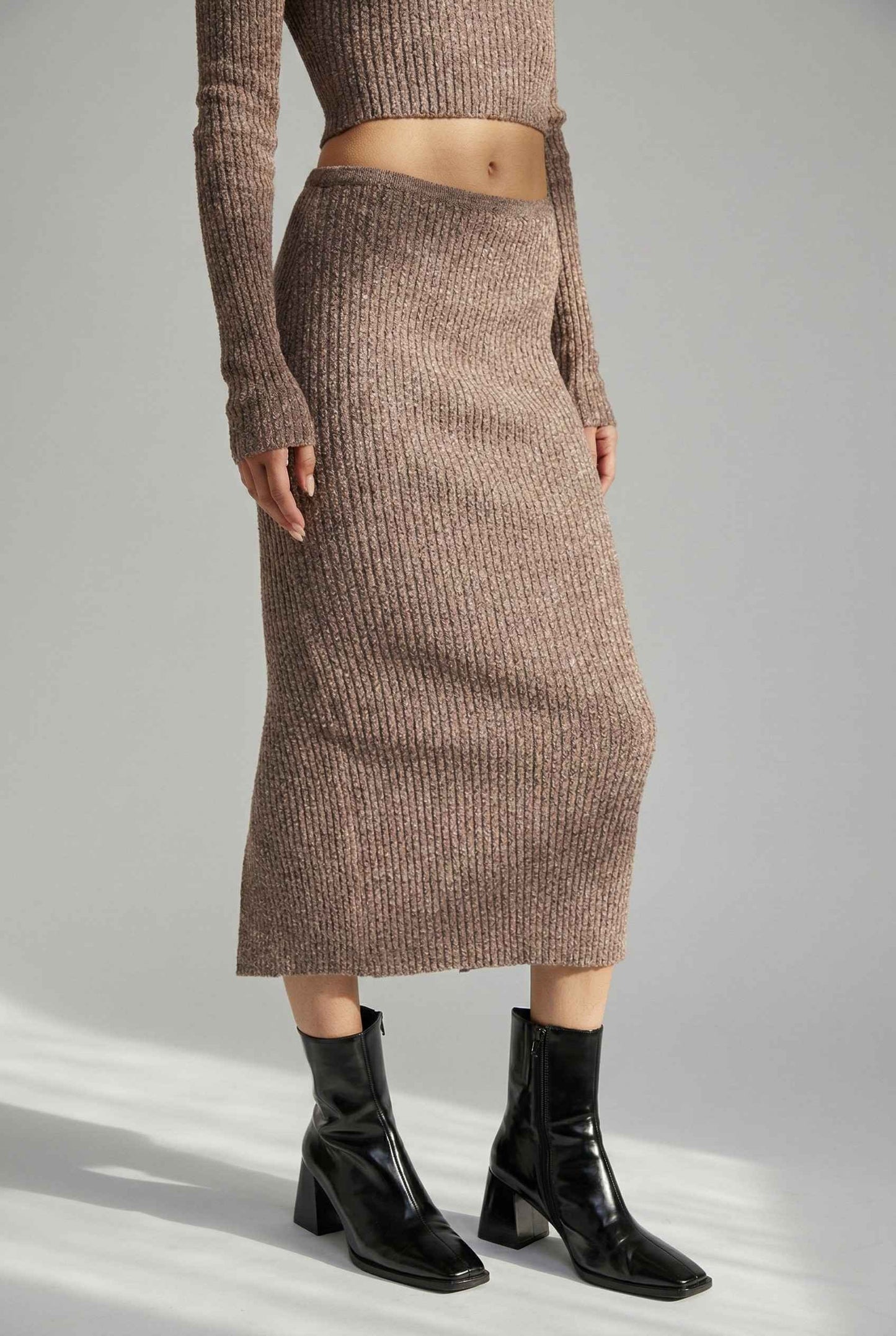 Model wearing Mila Skirt Marled Ribbed Knit Column Maxi Skirt in Brown with matching sweater top and heeled boots on a plain background