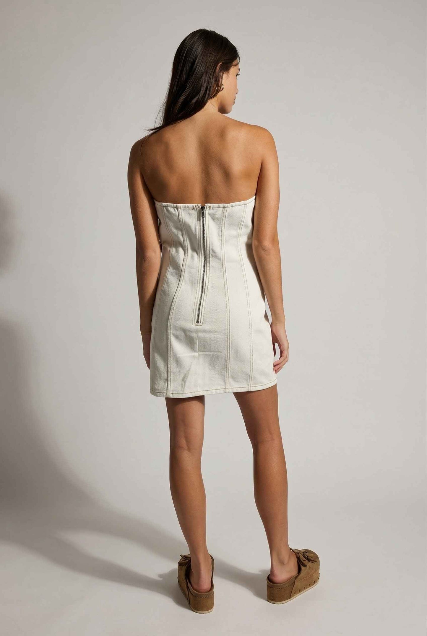 Model wearing Odette Mini in White Denim Strapless Rosette Dress with platform sandals