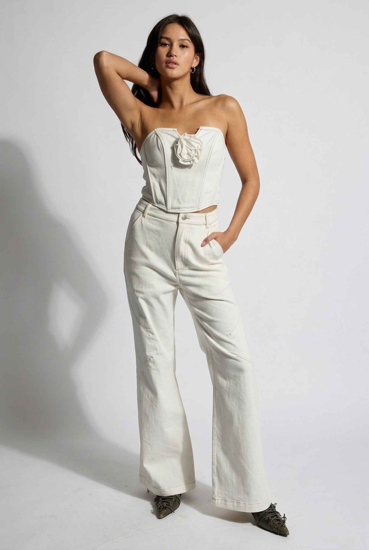 Model wearing Odette Top in White Cotton Denim Strapless Rosette Bustier with matching bootleg jeans and pointed heels