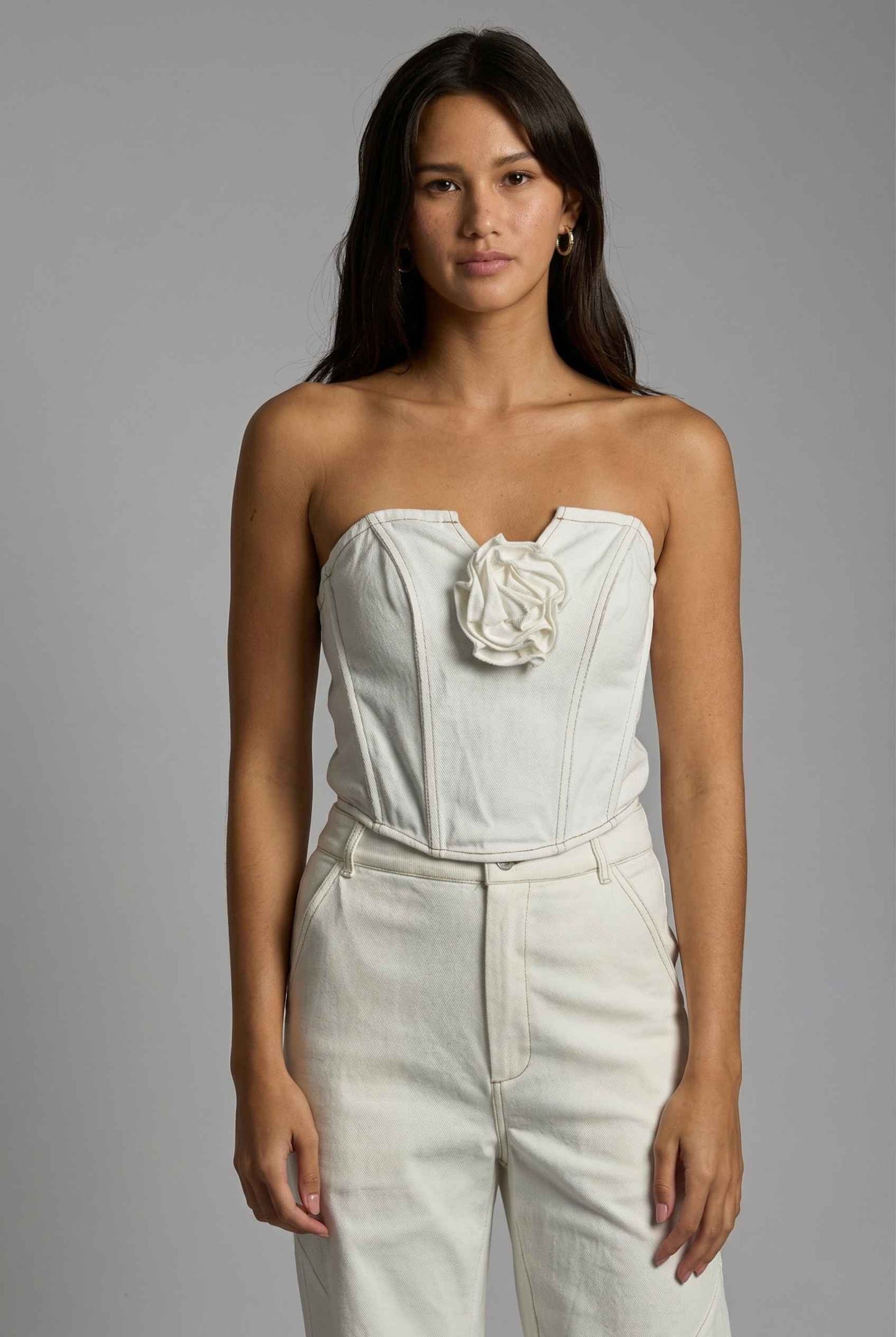 Model wearing Odette Top in White Cotton Denim Strapless Rosette Bustier with matching bootleg jeans 