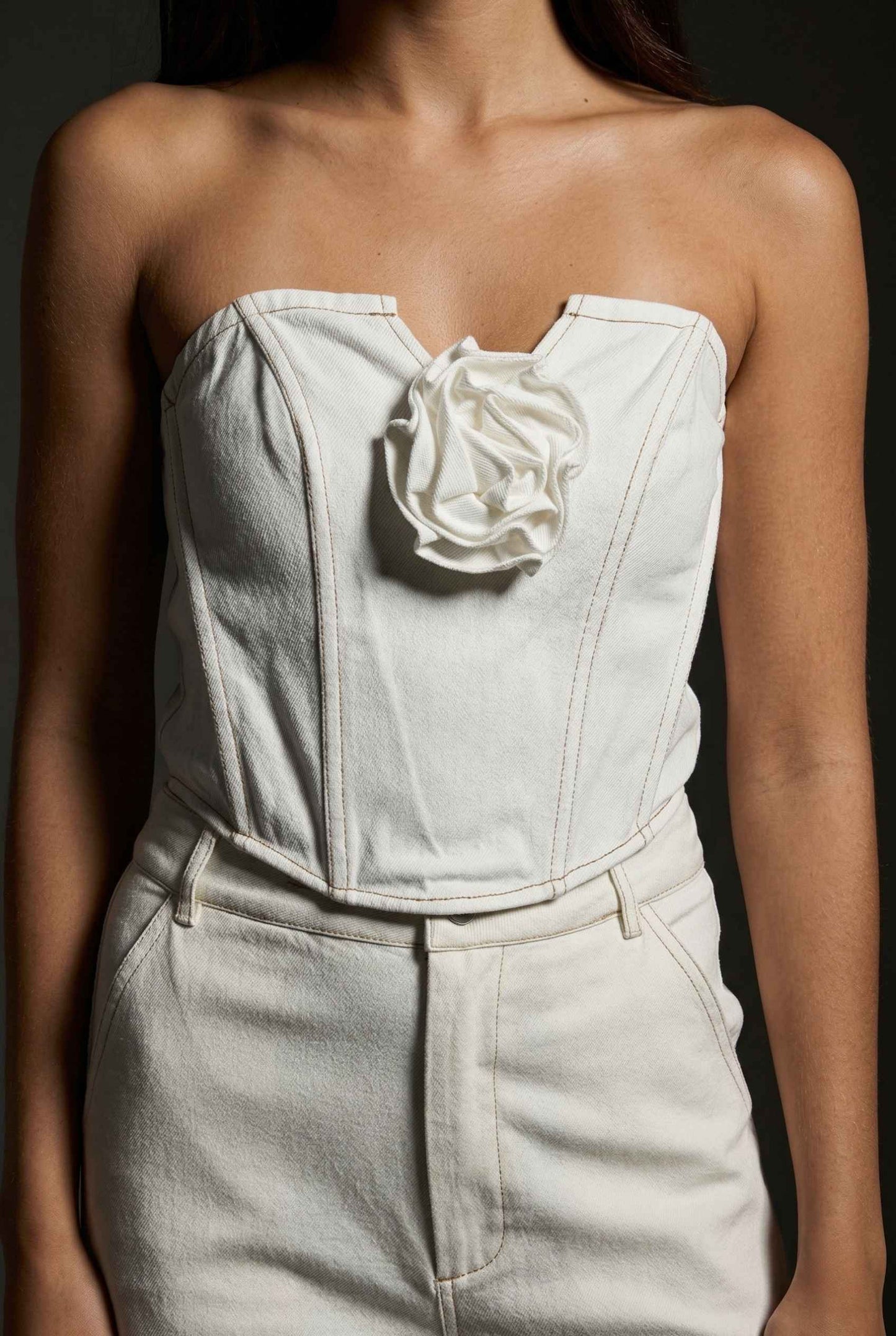 Model wearing Odette Top in White Cotton Denim Strapless Rosette Bustier with matching bootleg jeans 