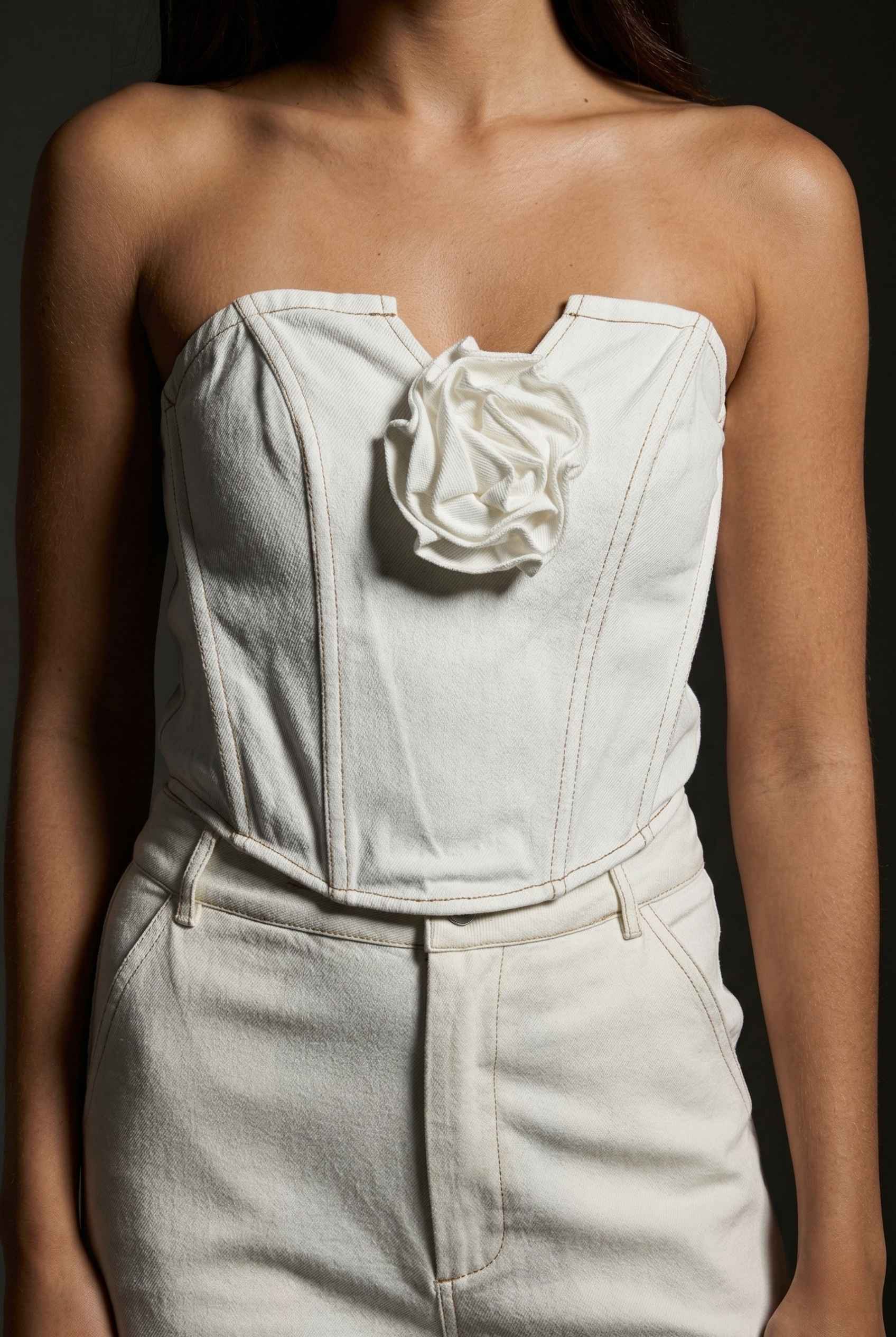 Model wearing Odette Top in White Cotton Denim Strapless Rosette Bustier with matching bootleg jeans 