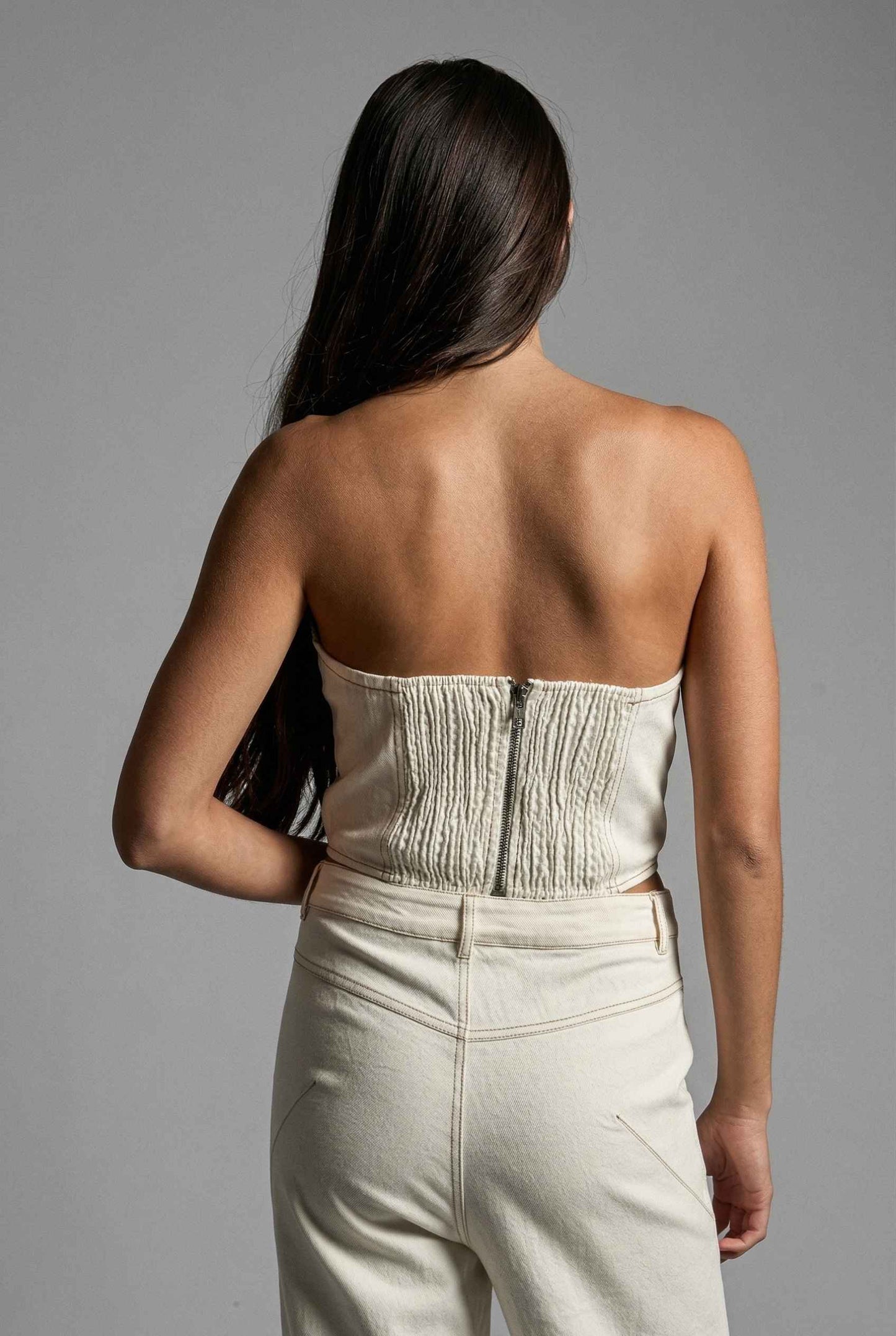 Model wearing Odette Top in White Cotton Denim Strapless Rosette Bustier with matching bootleg jeans
