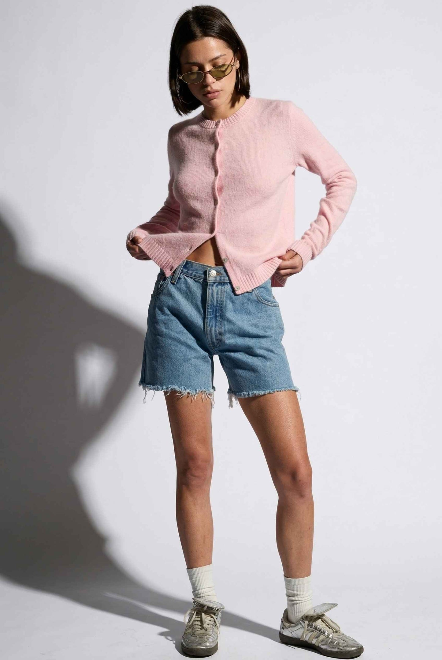 Model wearing Penelope Top in Pink Soft Wool-Blend Crew Neck Button-Up Cardigan with denim shorts and sneakers