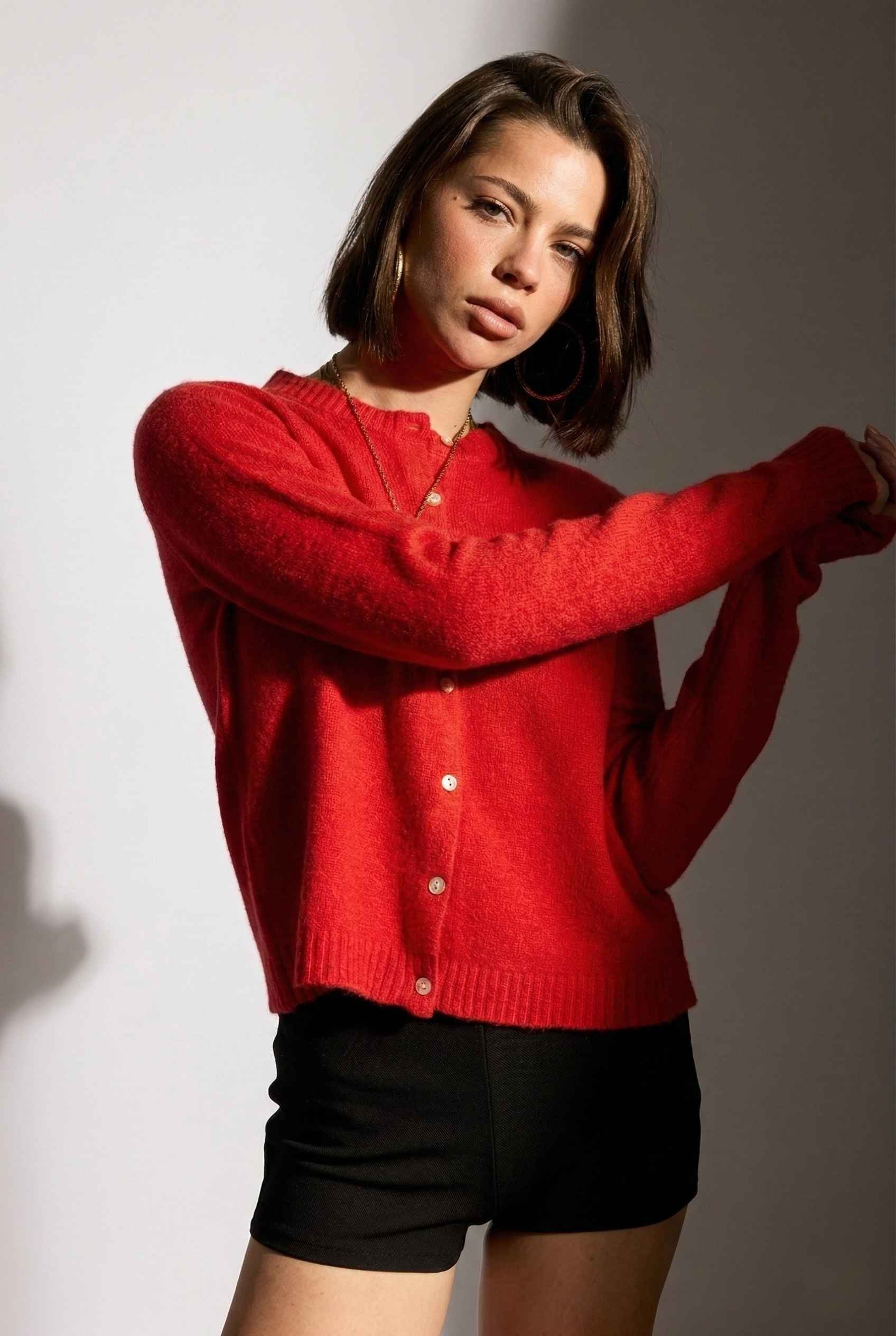 Model wearing Penelope Top in Red Soft Wool-Blend Crew Neck Button-Up Cardigan with micro shorts